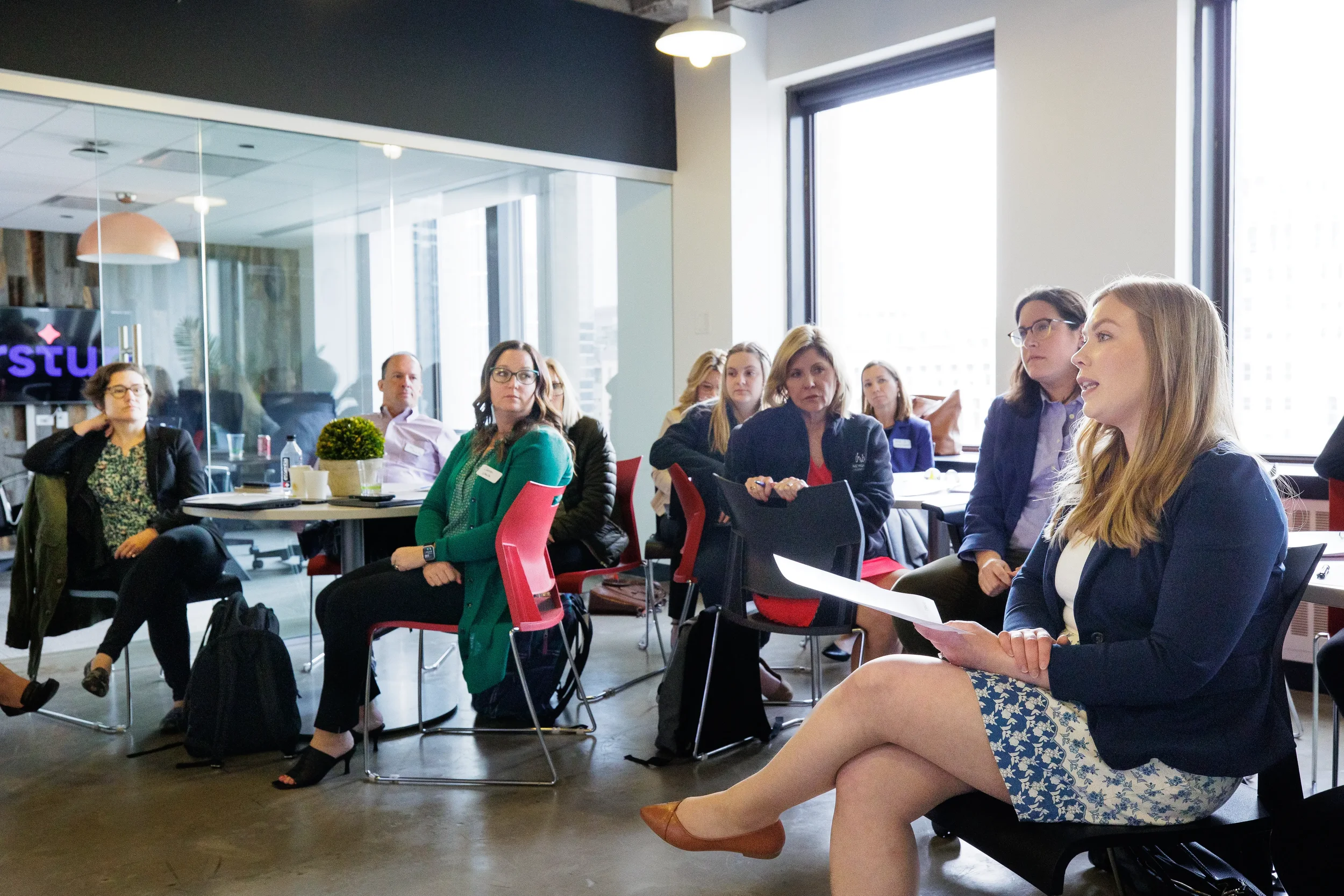 Female presenter addresses an attentive seated audience with notes in hand at Chicago corporate event