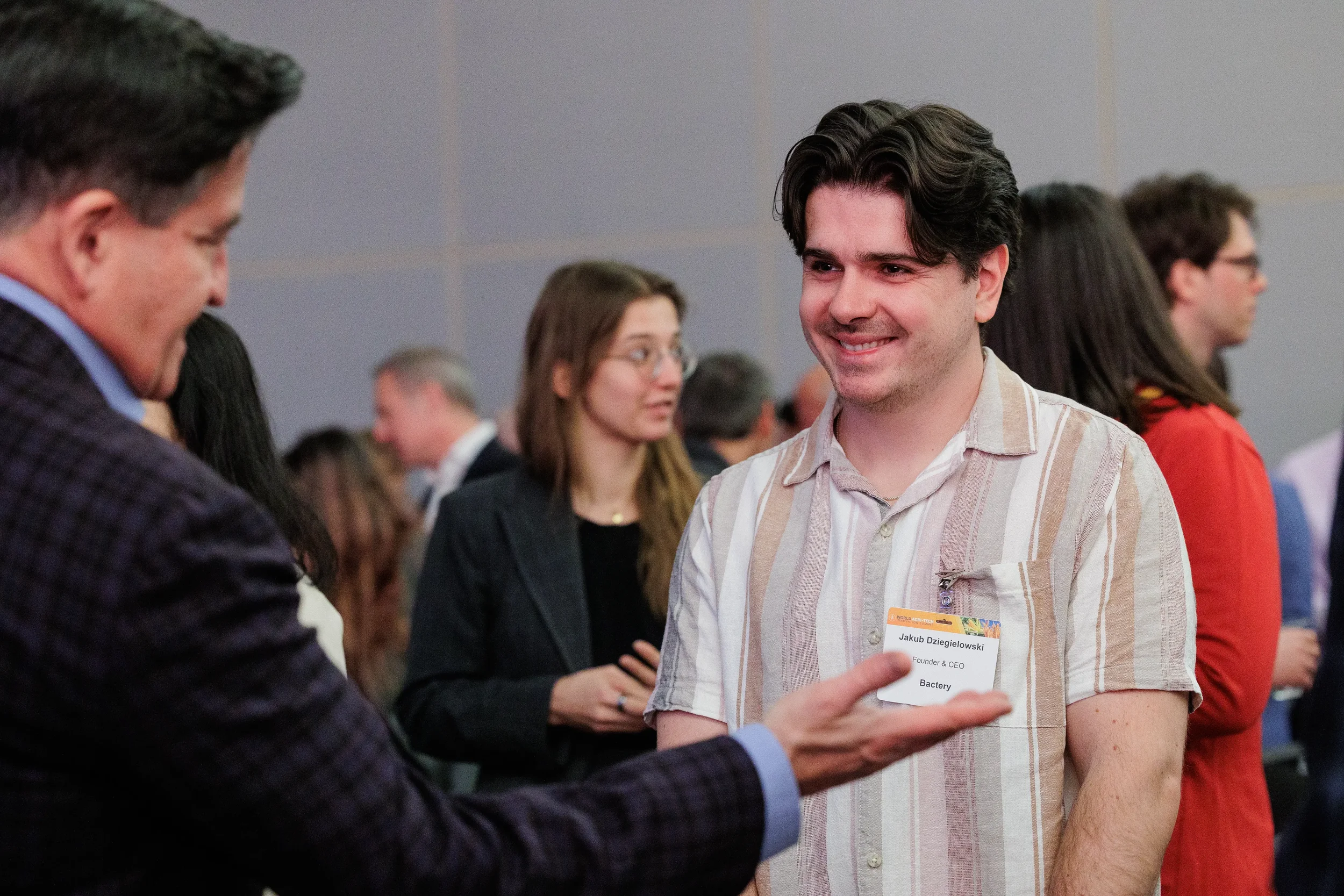 Attendee with name badge smiles during networking reception among group at Orlando corporate conference