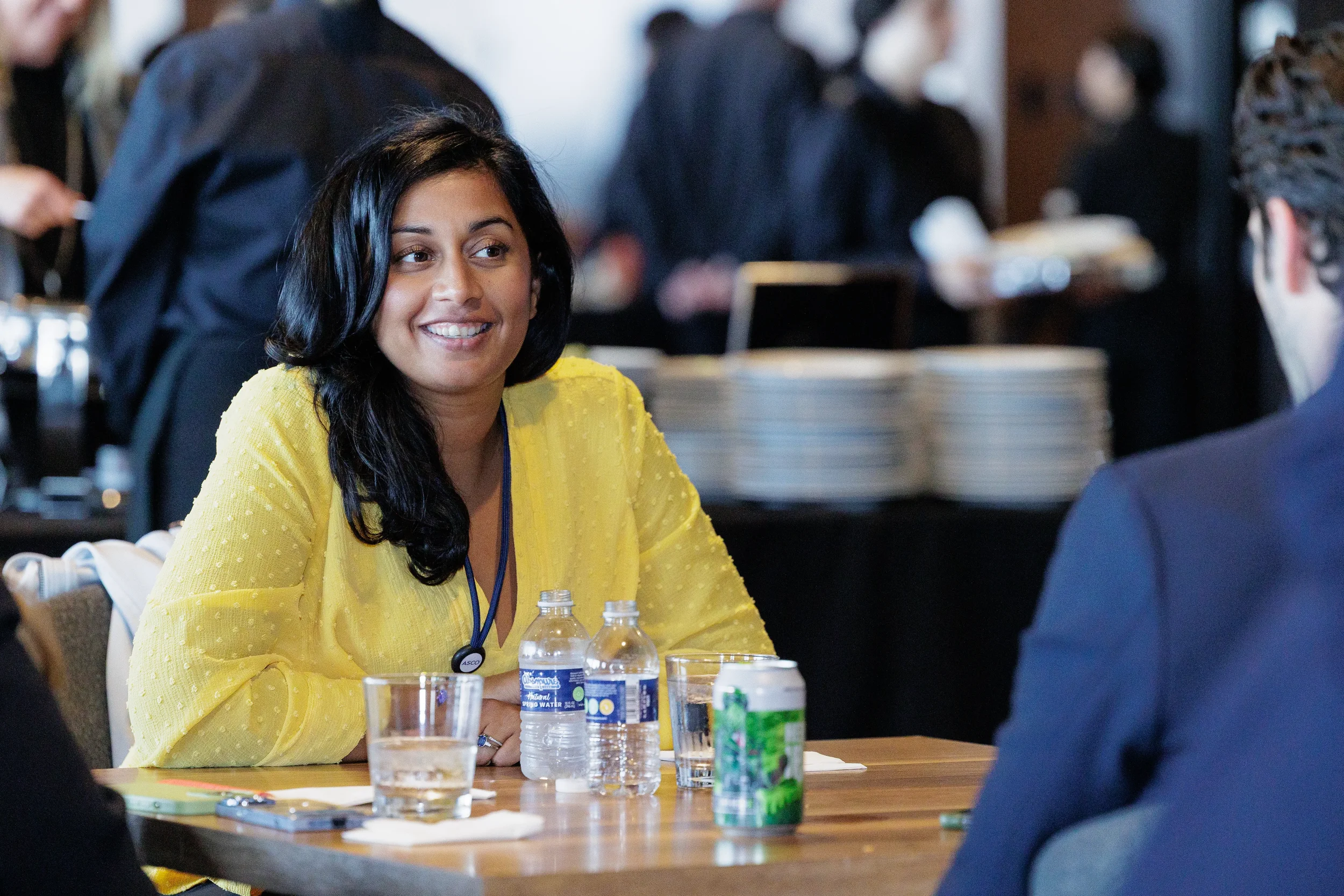 Attendee smiles during conversation at seated table during Orlando industry conference break