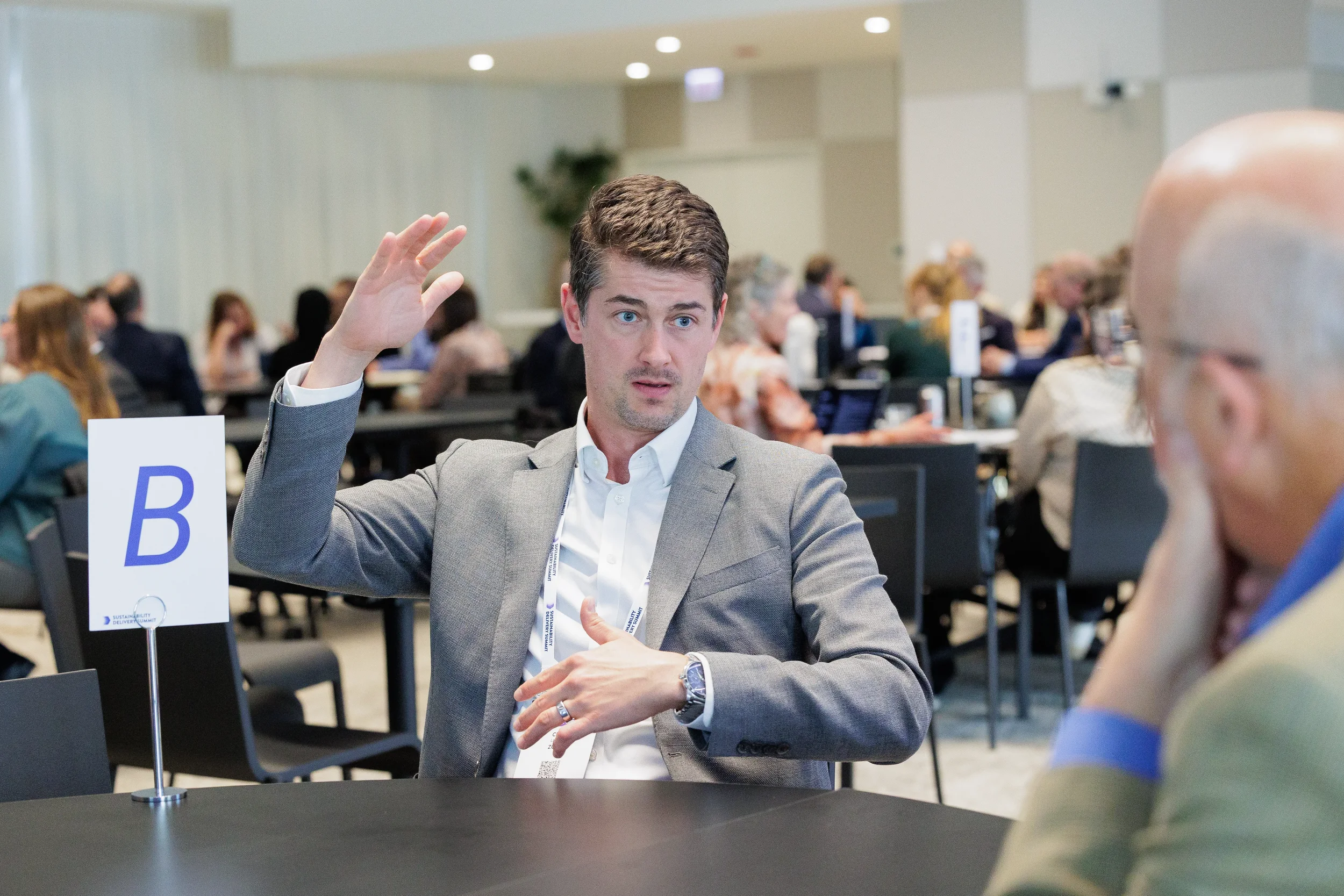 Attendee gestures during roundtable discussion while seated at Chicago industry conference session