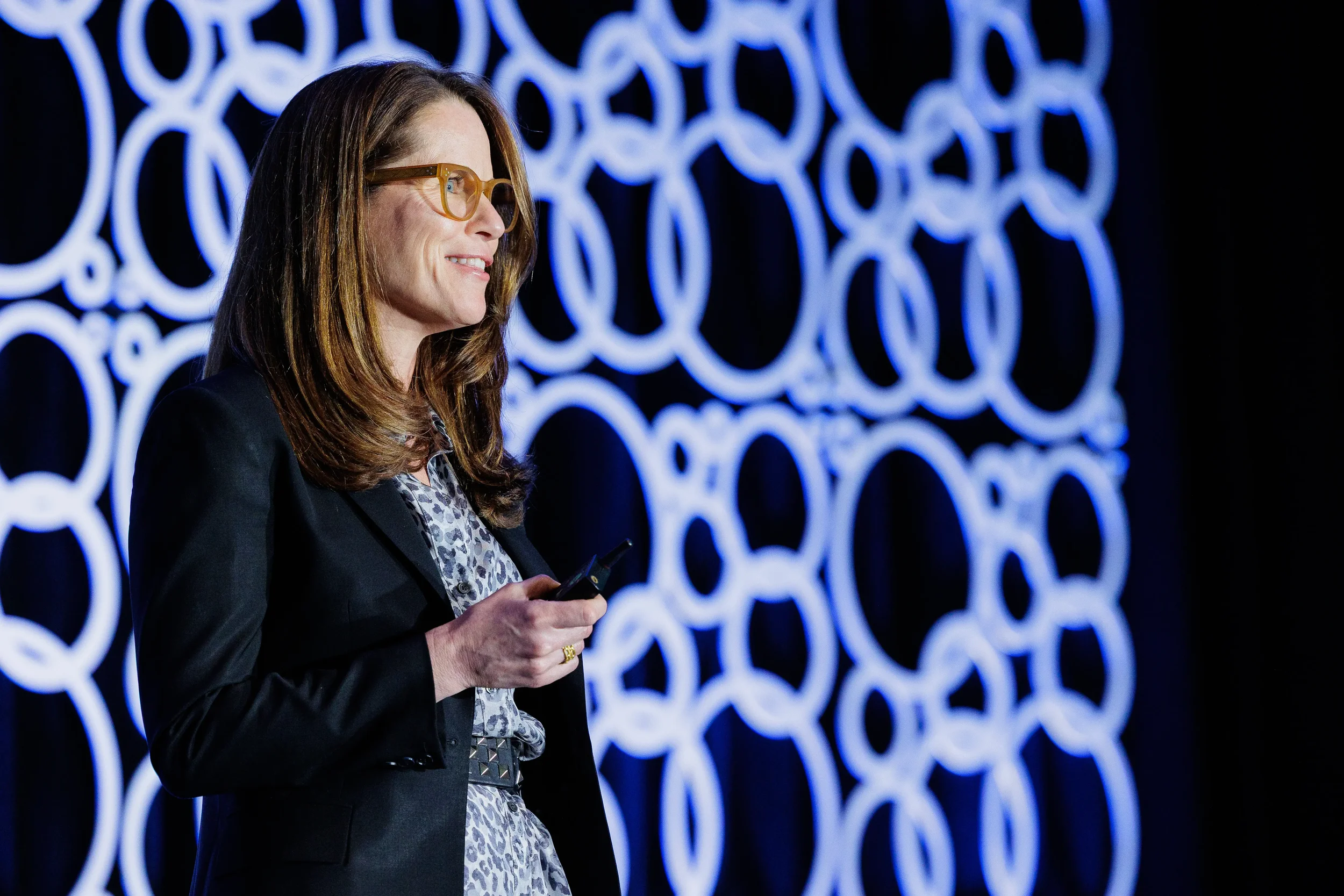 Speaker presents on stage with illuminated circular backdrop at Chicago industry conference