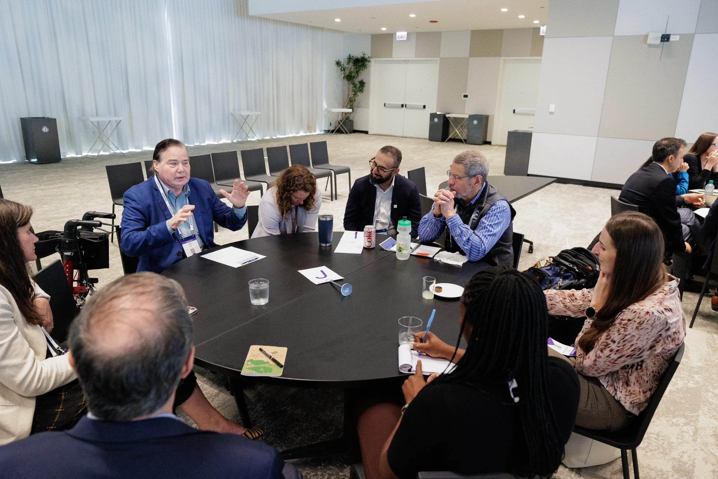 Speaker gestures while leading roundtable discussion with attendees at Orlando industry conference