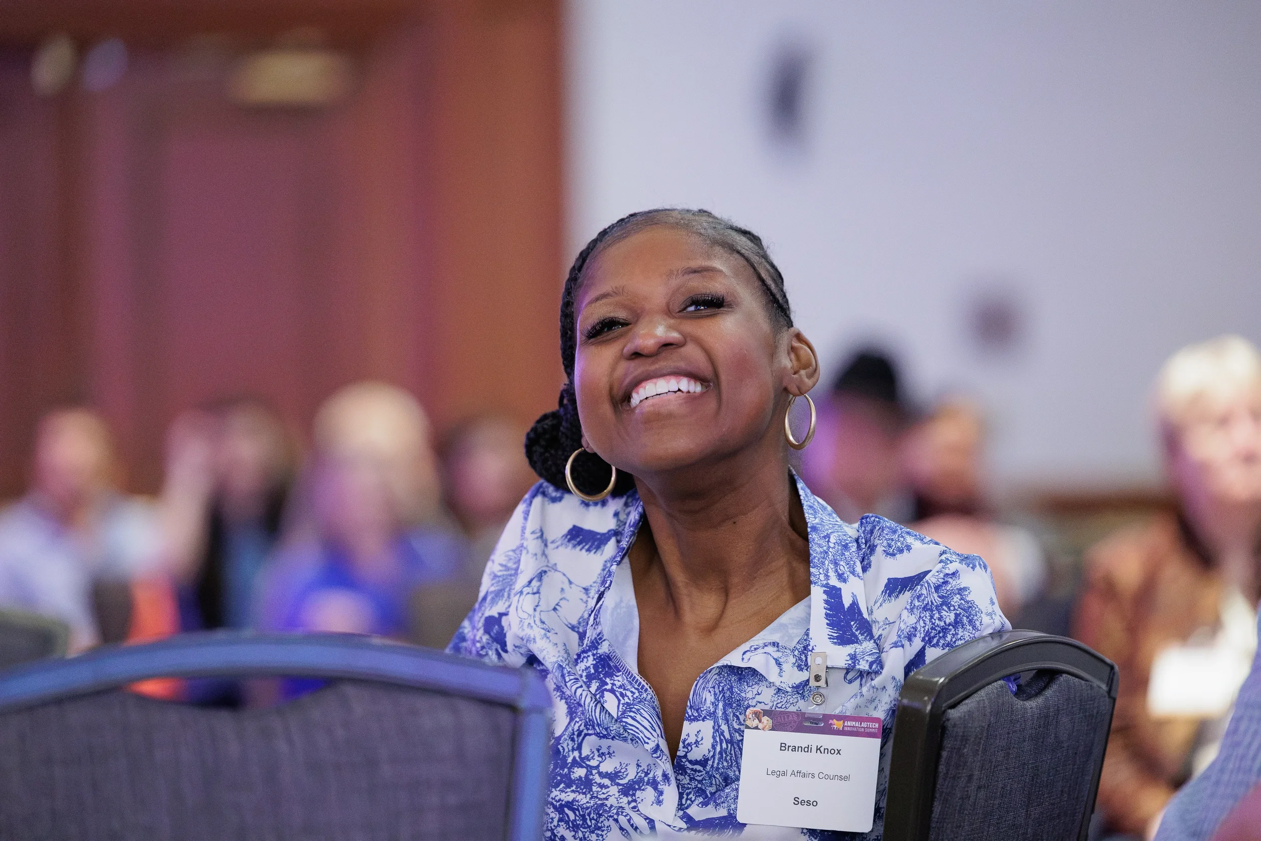 Attendee smiles while seated in audience during session at Orlando industry conference