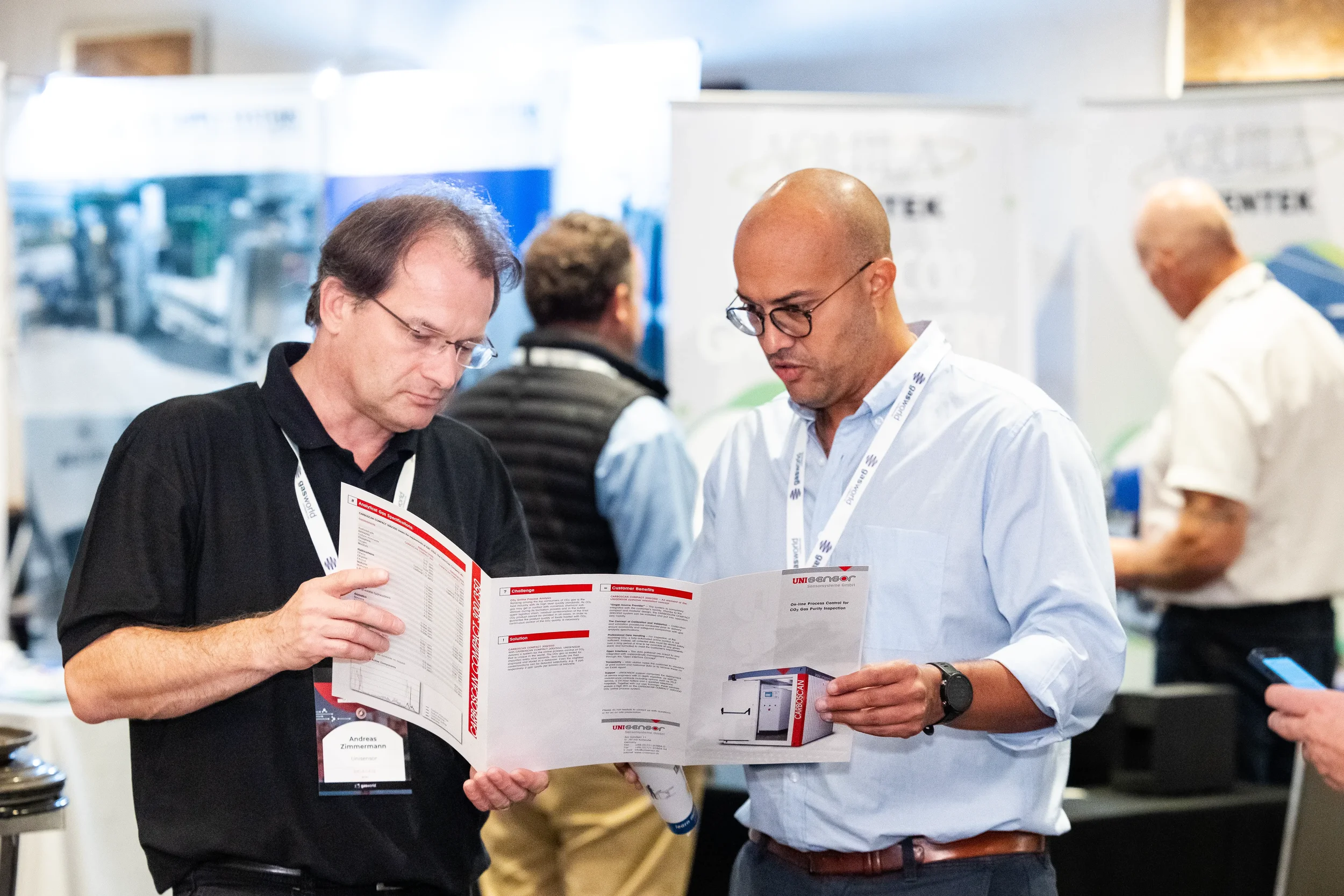Two attendees review product brochure together on expo floor at Orlando trade show