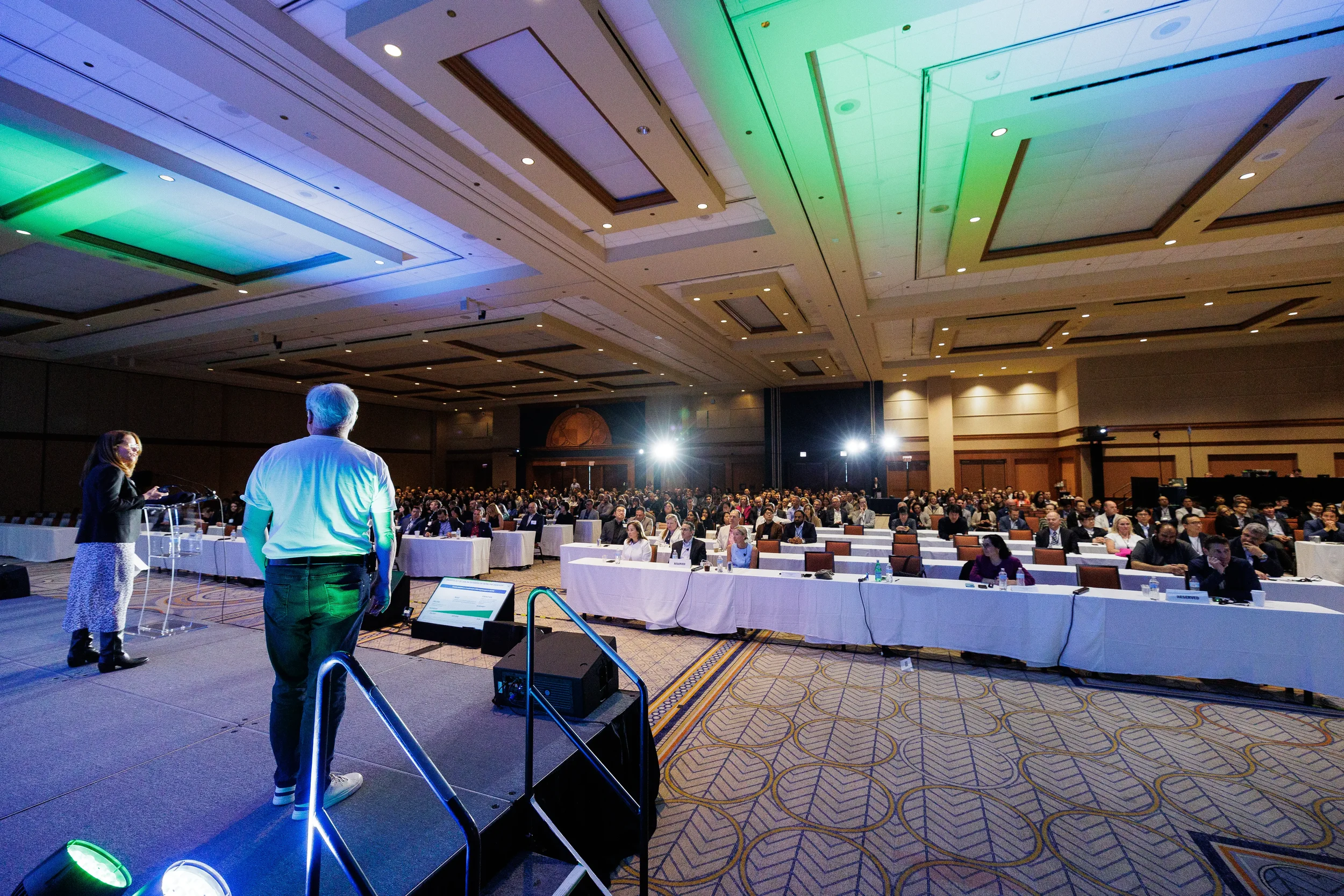 Wide view of speakers addressing seated audience in ballroom at Orlando industry conference