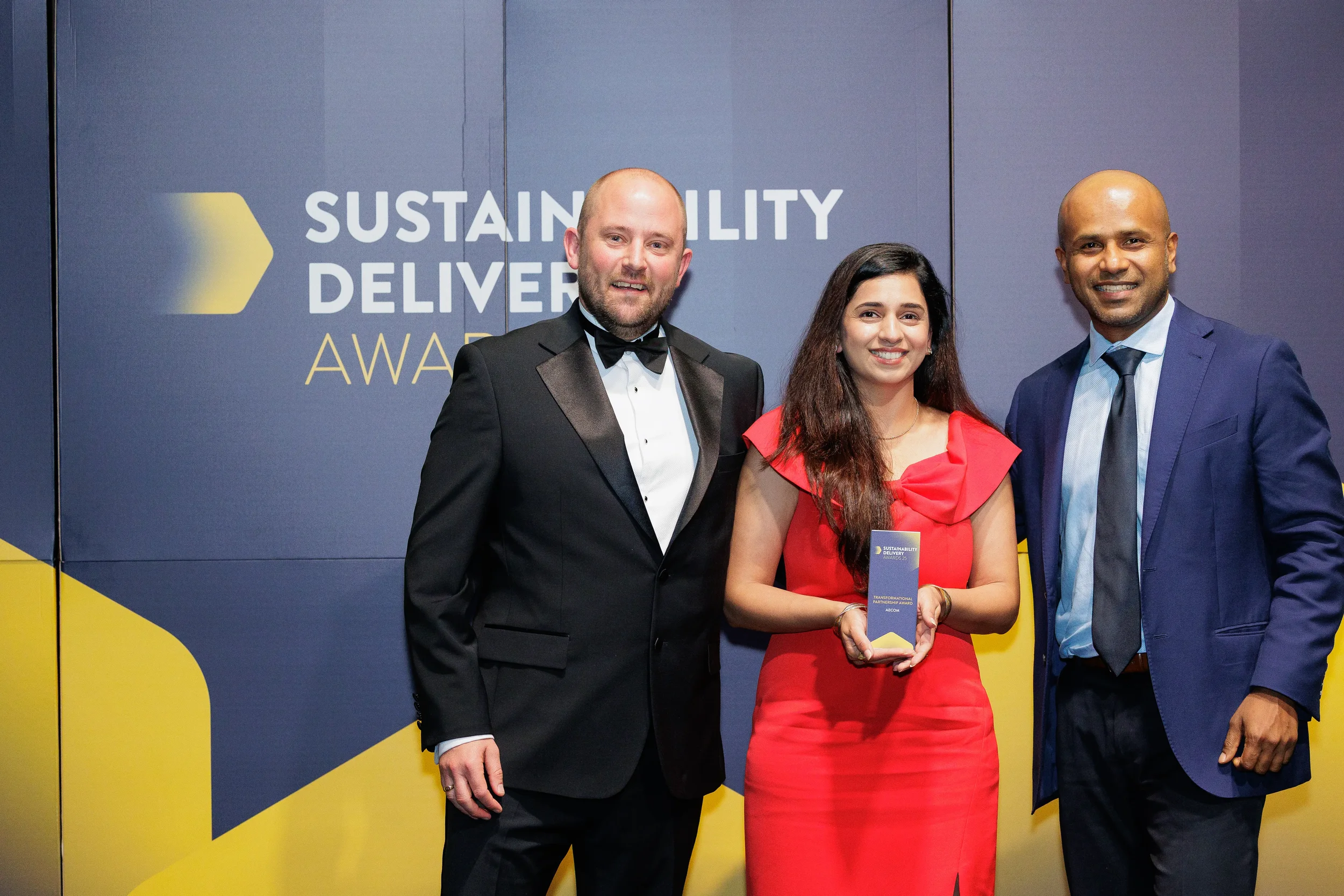 Award recipients pose with trophy on stage in formal attire at Chicago corporate event