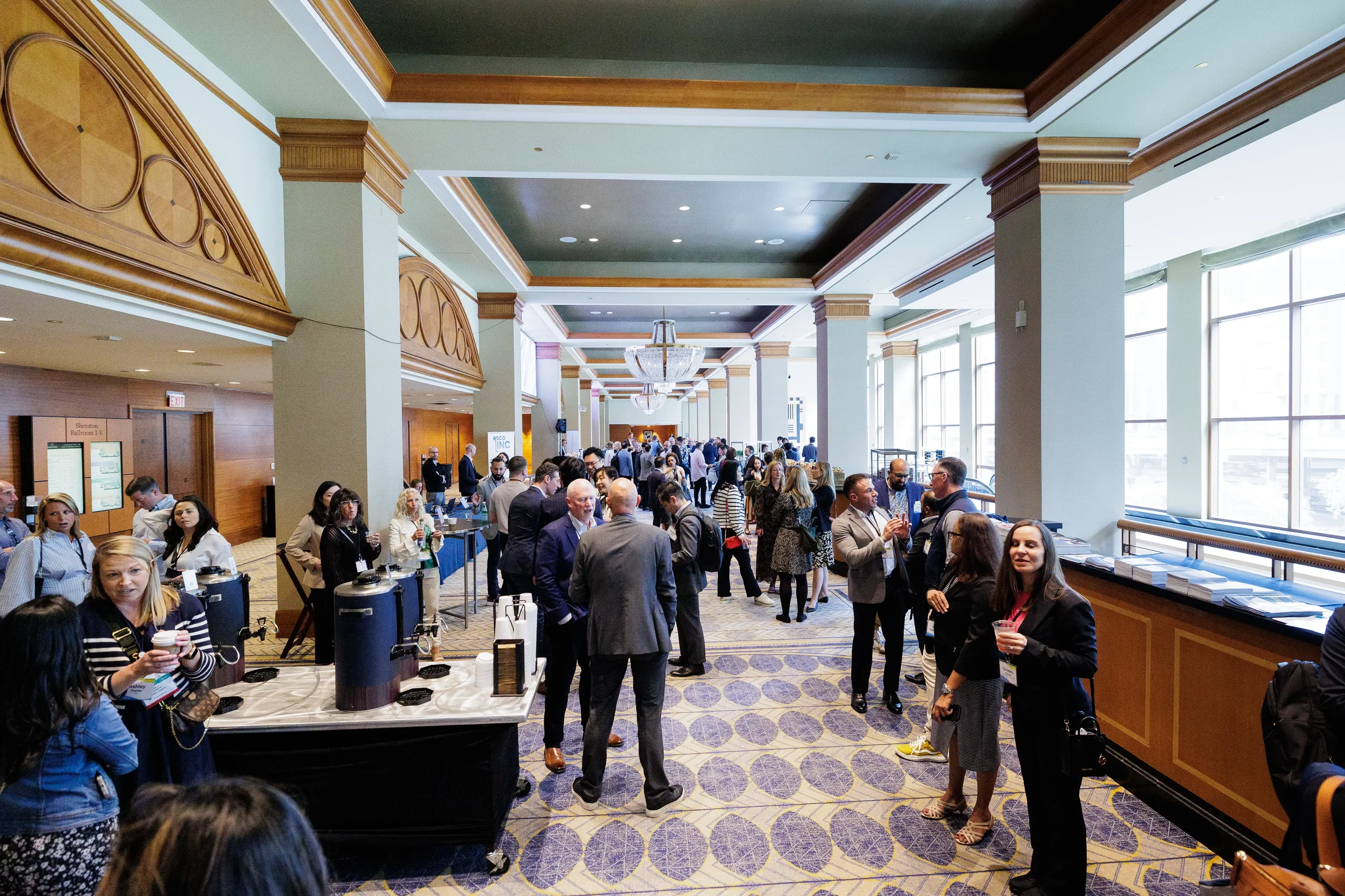 Attendees network in conference hallway near coffee stations at Chicago industry event