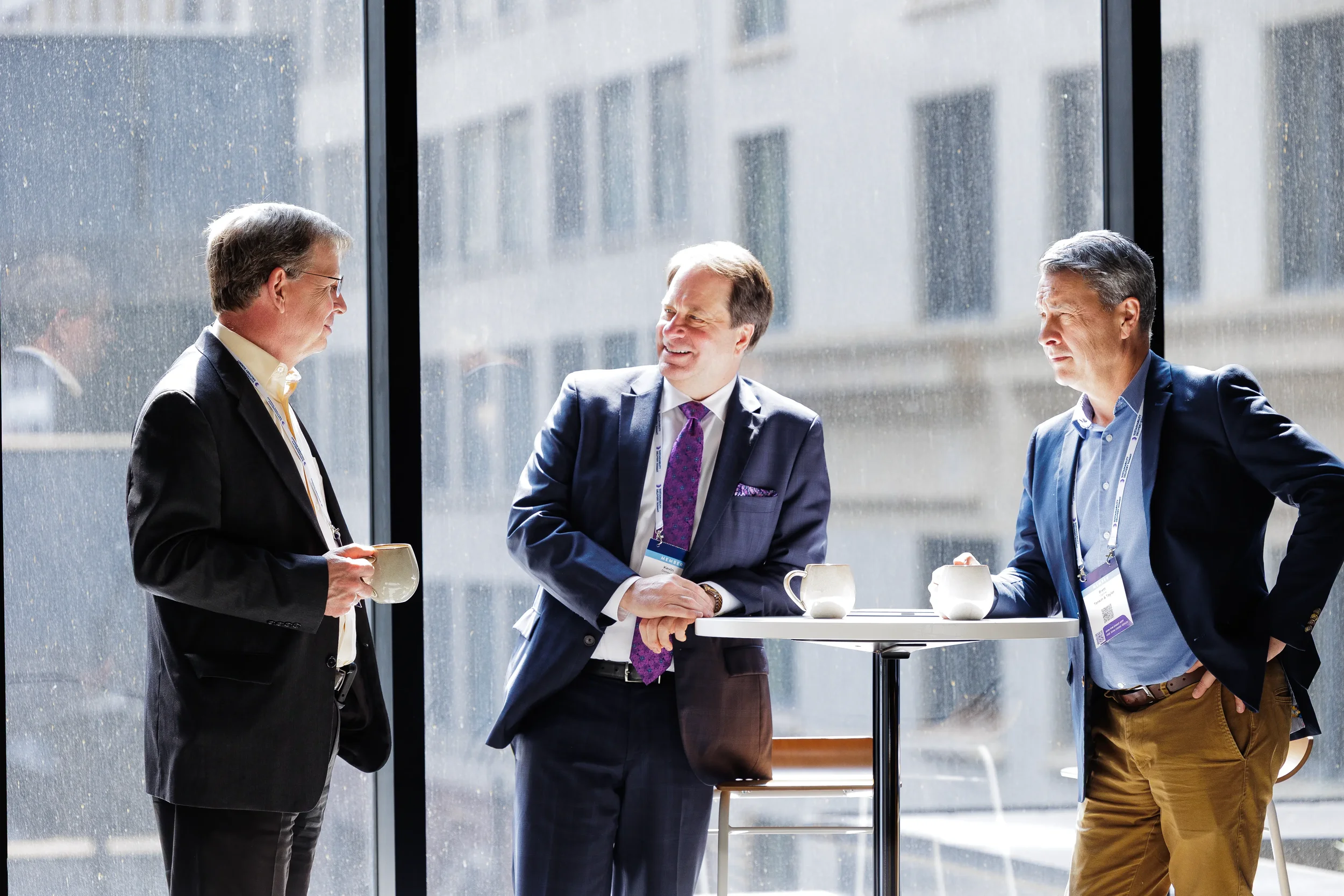 Three attendees converse at standing table over coffee during Orlando corporate conference