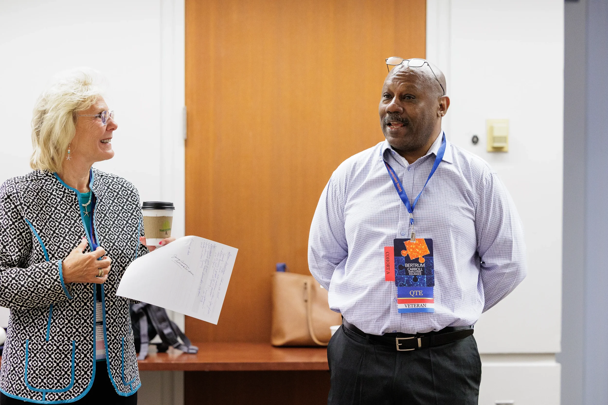 Two attendees with lanyards smile and converse during break at Chicago industry conference session