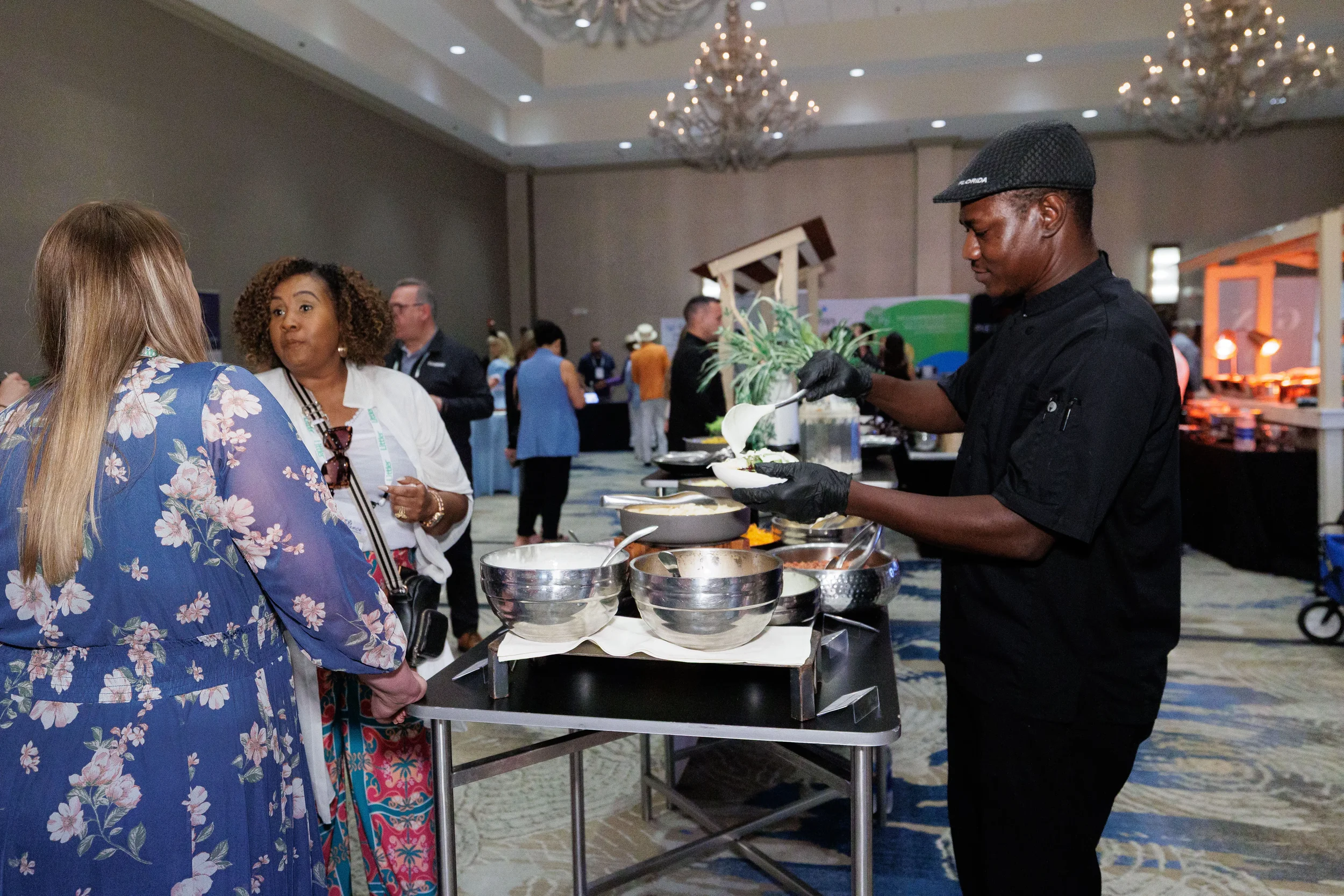 Chef in black serves food to attendees at catering station on Orlando corporate conference expo floor