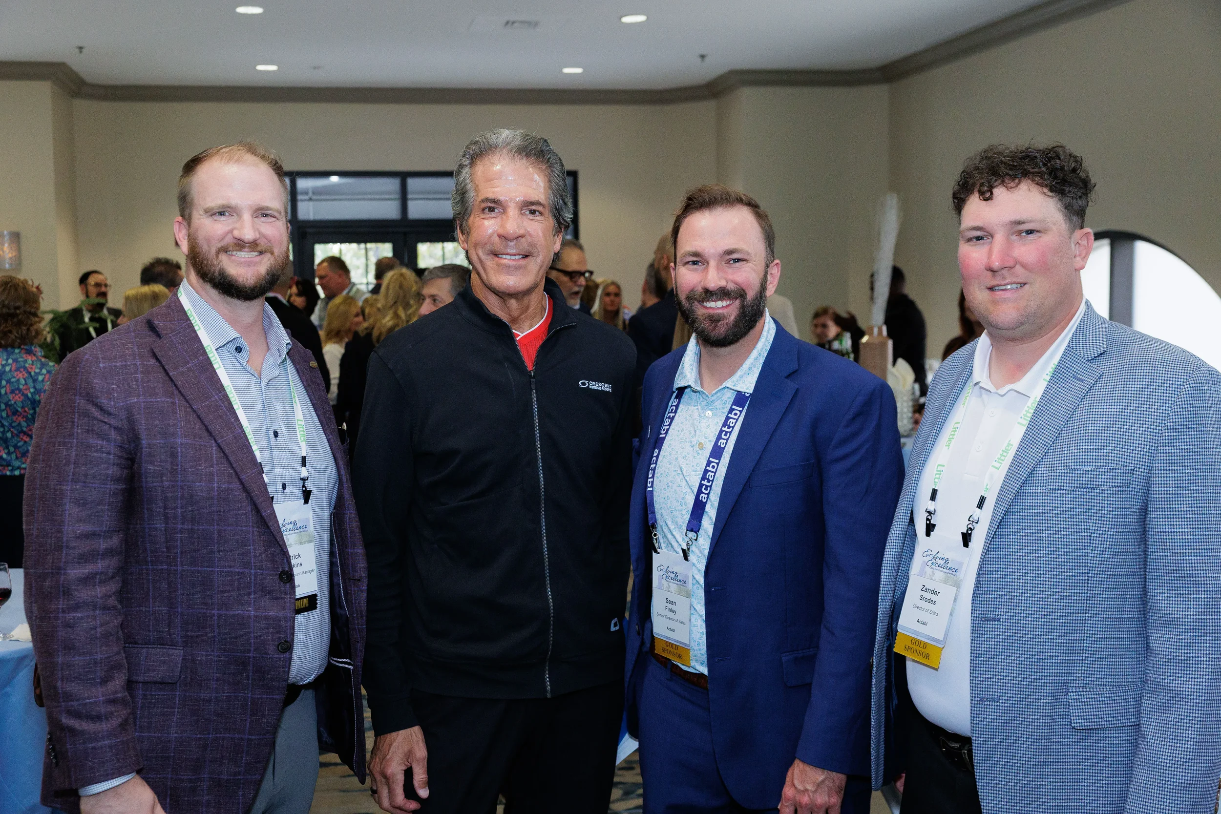 Four male attendees with lanyards smile together during Orlando corporate conference networking reception
