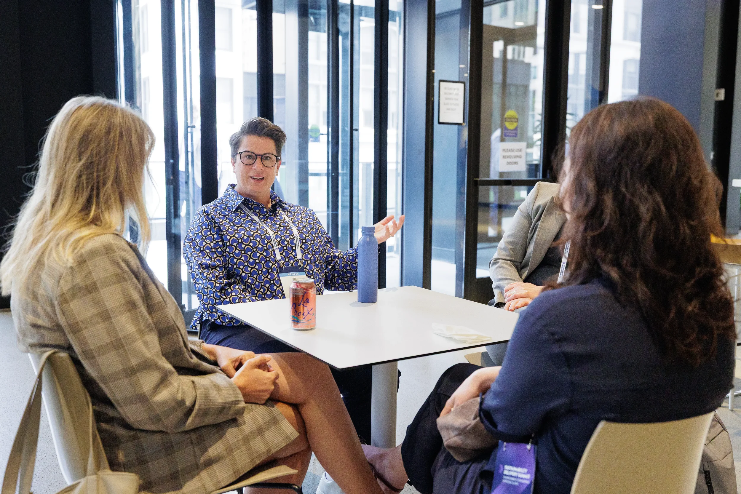 Attendees converse at standing table near window during Chicago industry conference