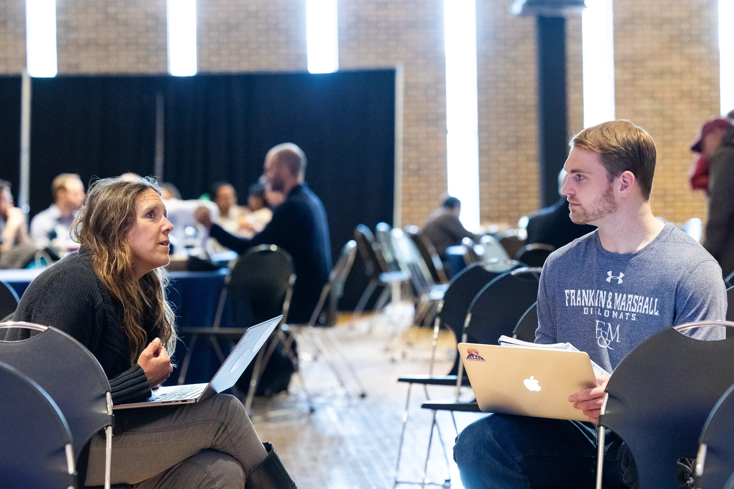 Two attendees with laptops engage in conversation during break at Chicago corporate conference