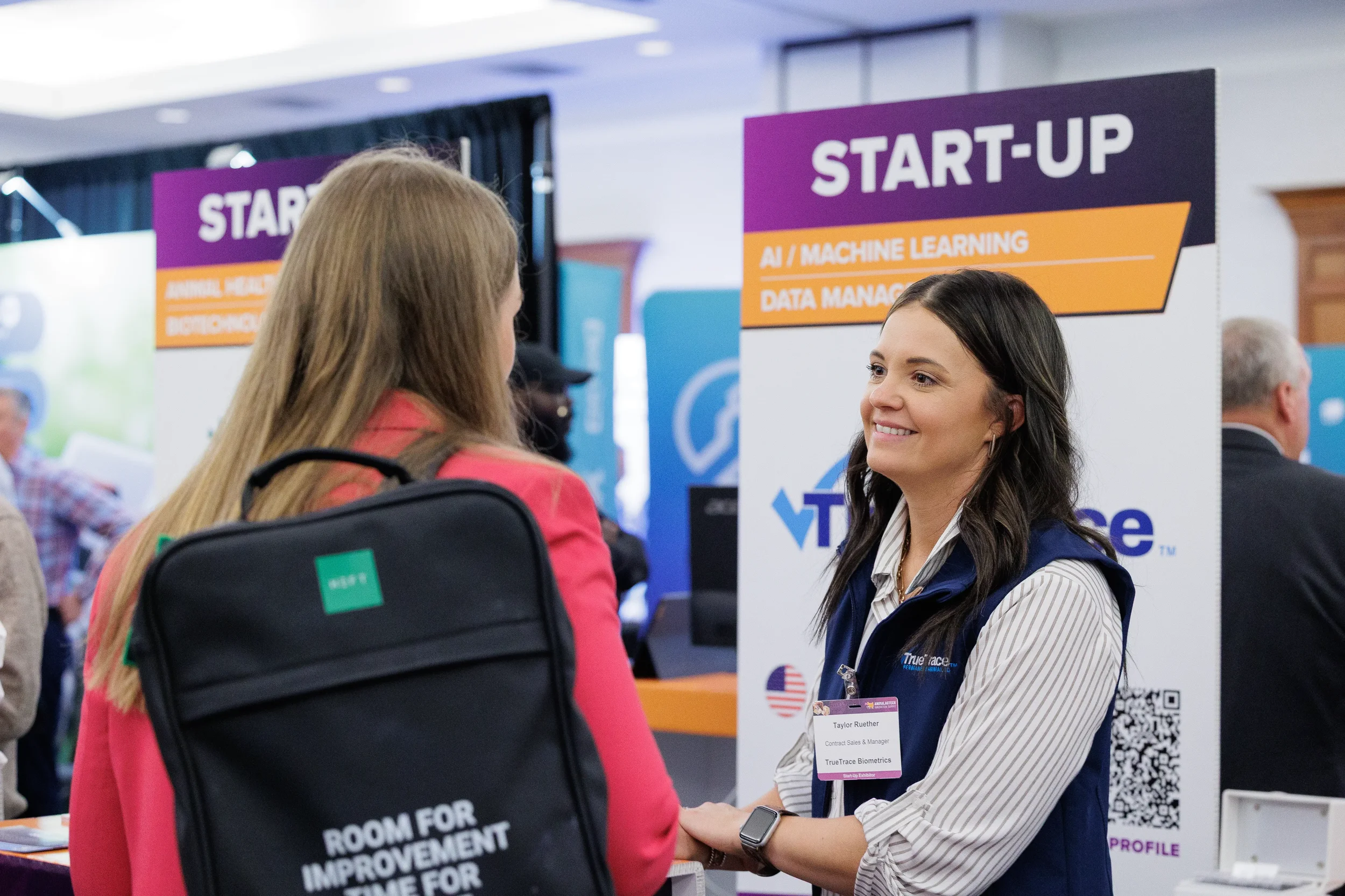 Attendees converse at startup expo booth during Orlando industry trade show