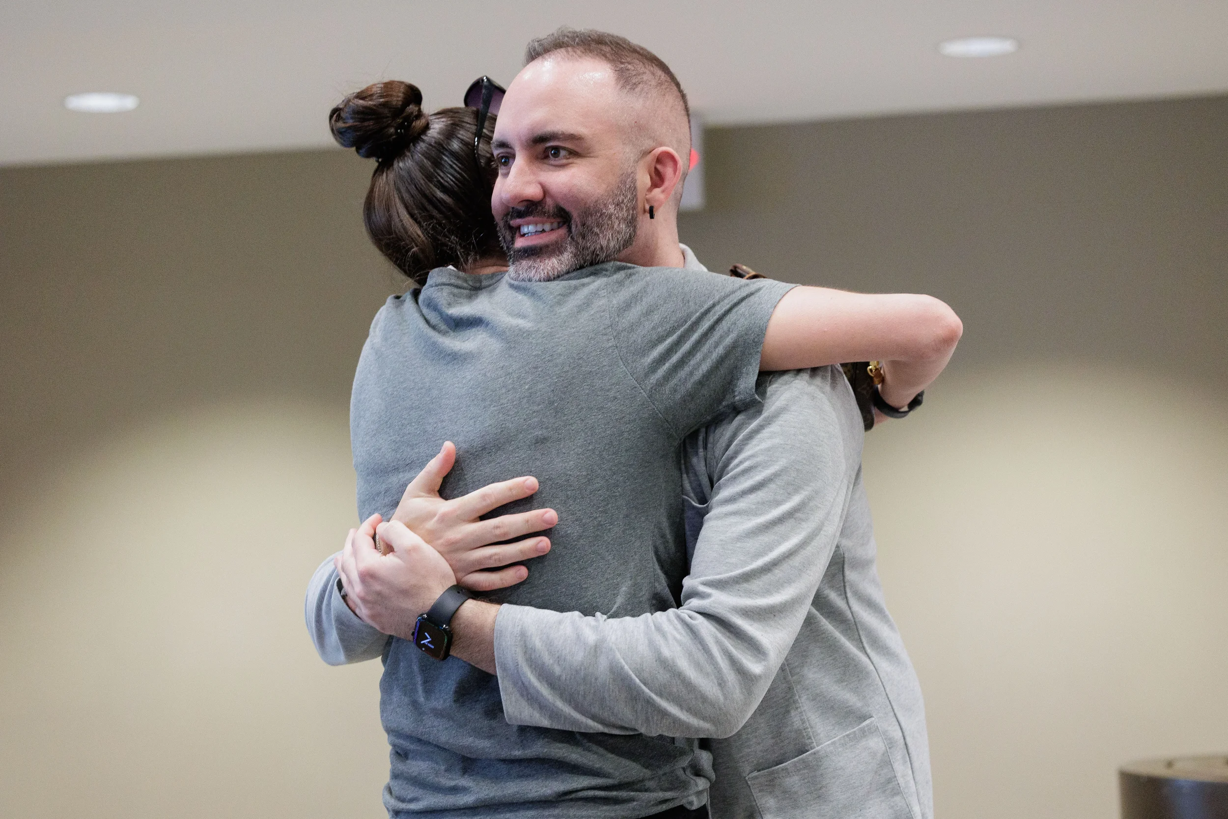 Two attendees share a warm hug and smile at Orlando corporate conference networking event