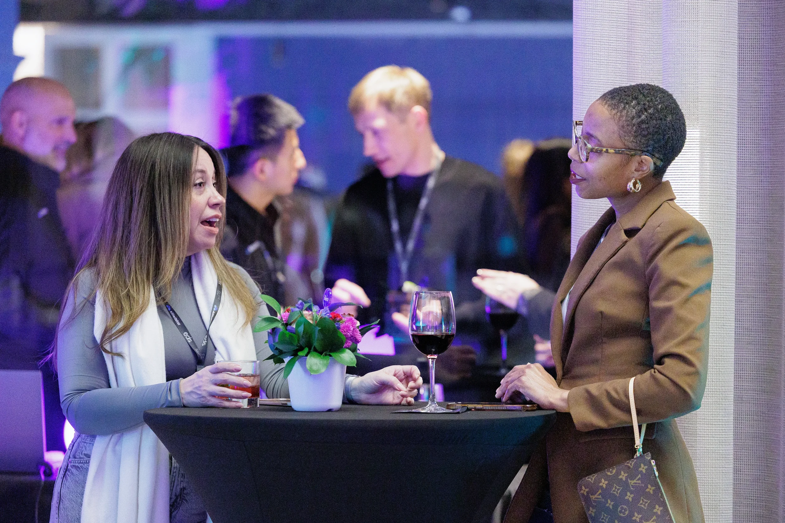 Two women converse over drinks at floral cocktail table during Chicago corporate event reception