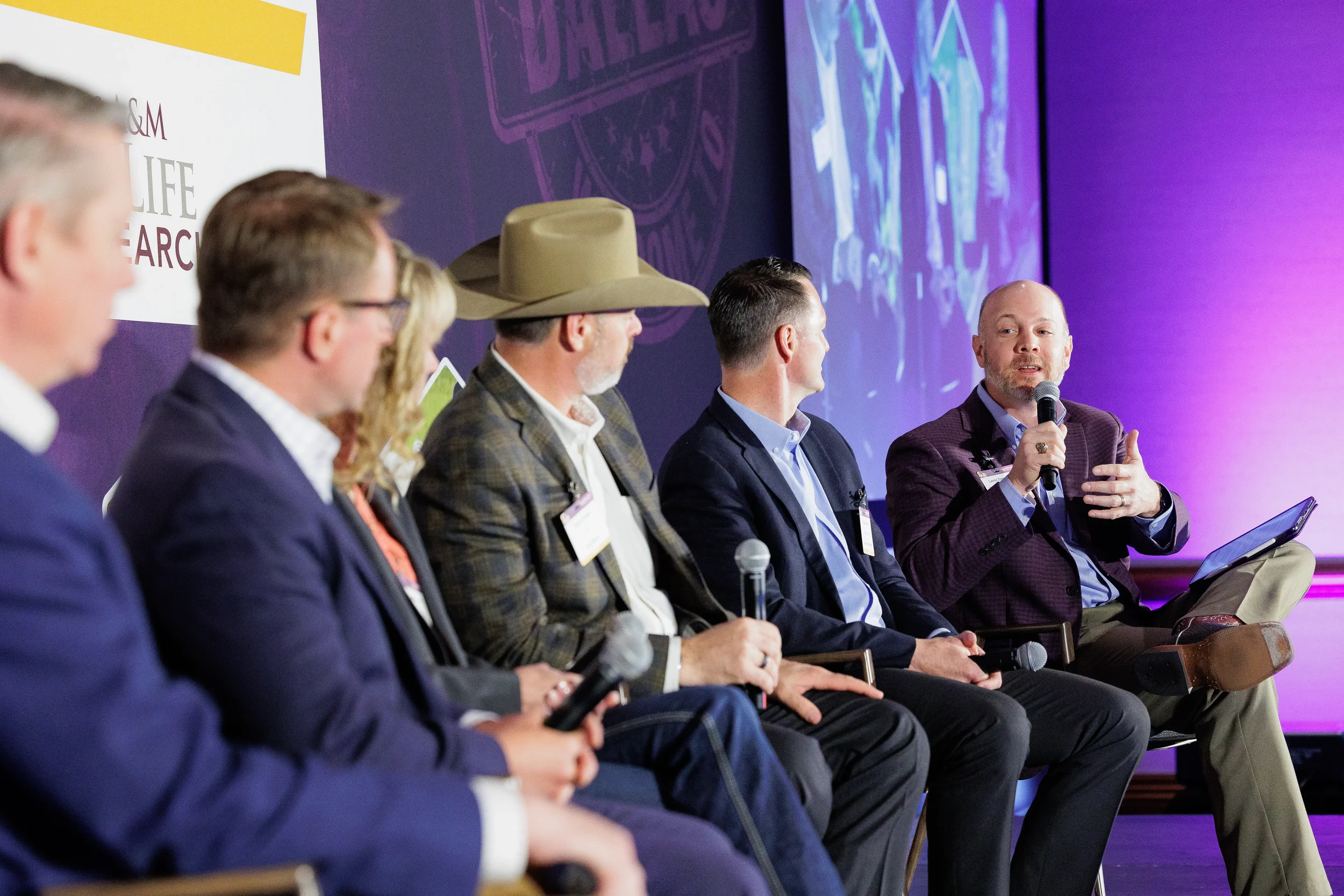 Panelist gestures while speaking on stage during panel discussion at Orlando corporate summit