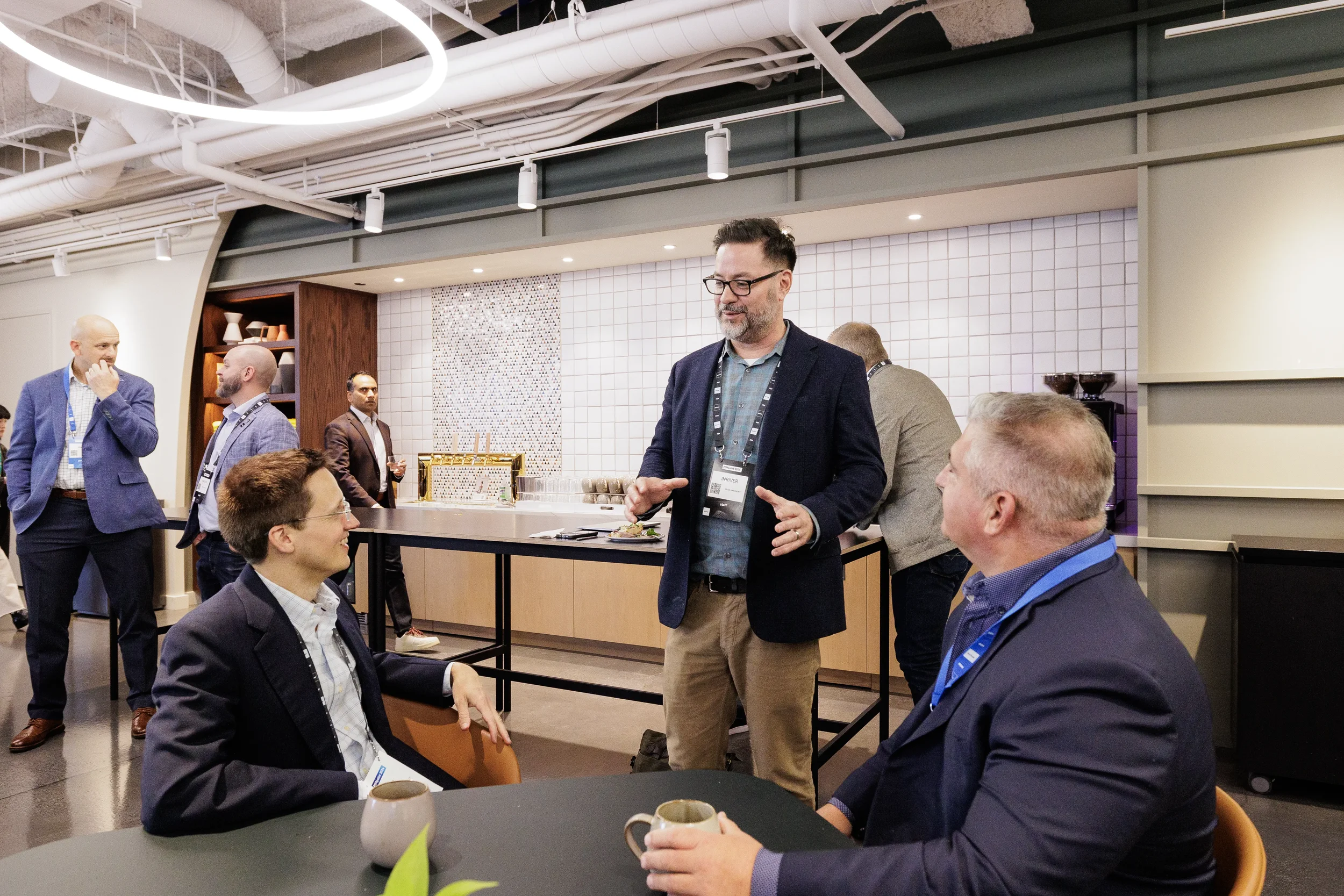 Attendees with lanyards chat over coffee in lounge during networking break at Orlando corporate event