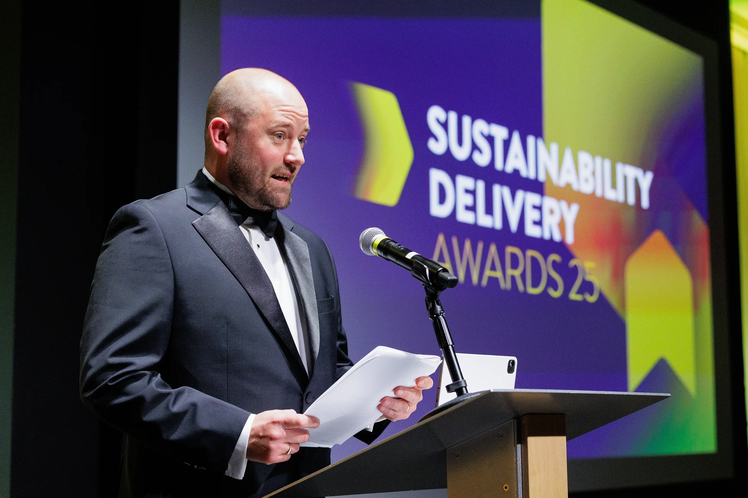 Host reads from podium on stage during Orlando corporate event awards ceremony