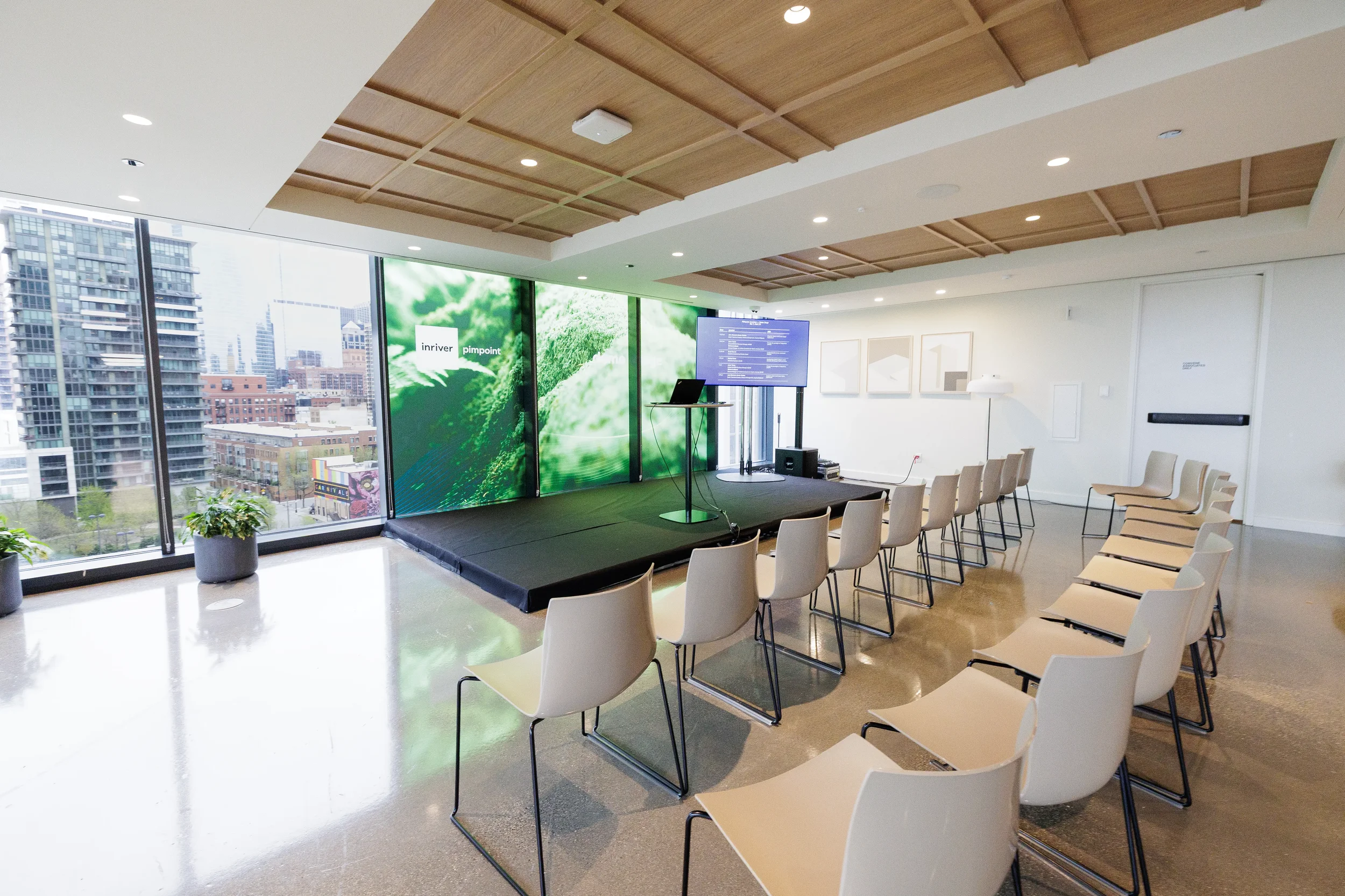 Empty chairs face stage with green backdrop and city view before session at Chicago industry conference