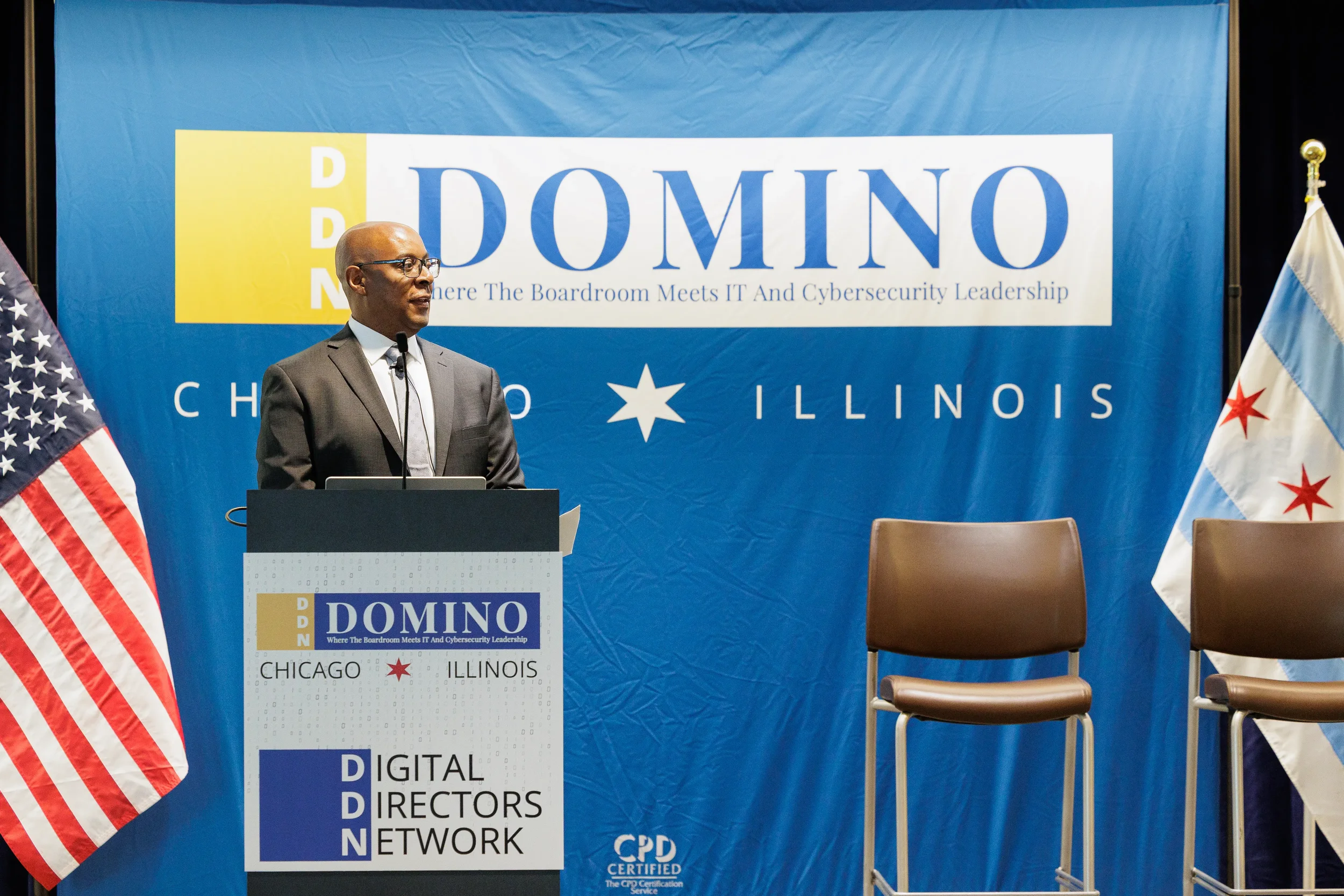 Speaker presents from branded podium on stage with American and Chicago flags at Chicago corporate event