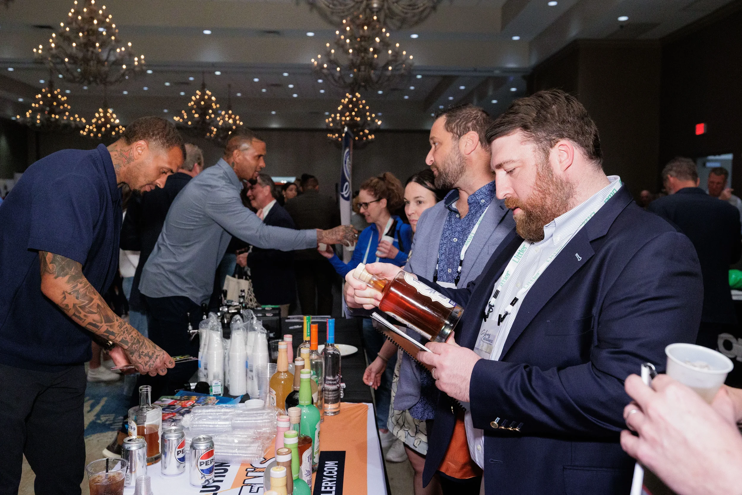 Attendees sample bottles at exhibitor booth in chandelier ballroom at Chicago corporate conference expo