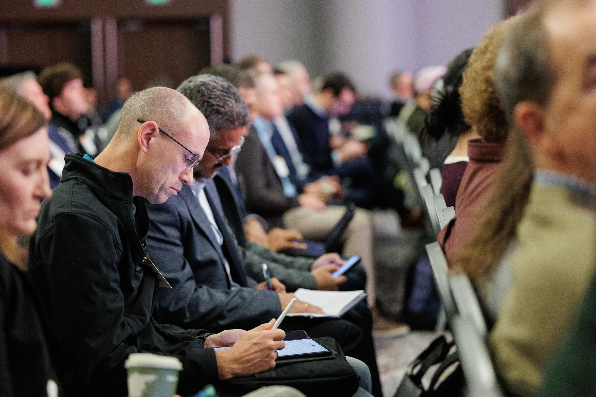Rows of attendees take notes on tablets and notebooks during session at Chicago corporate industry conference