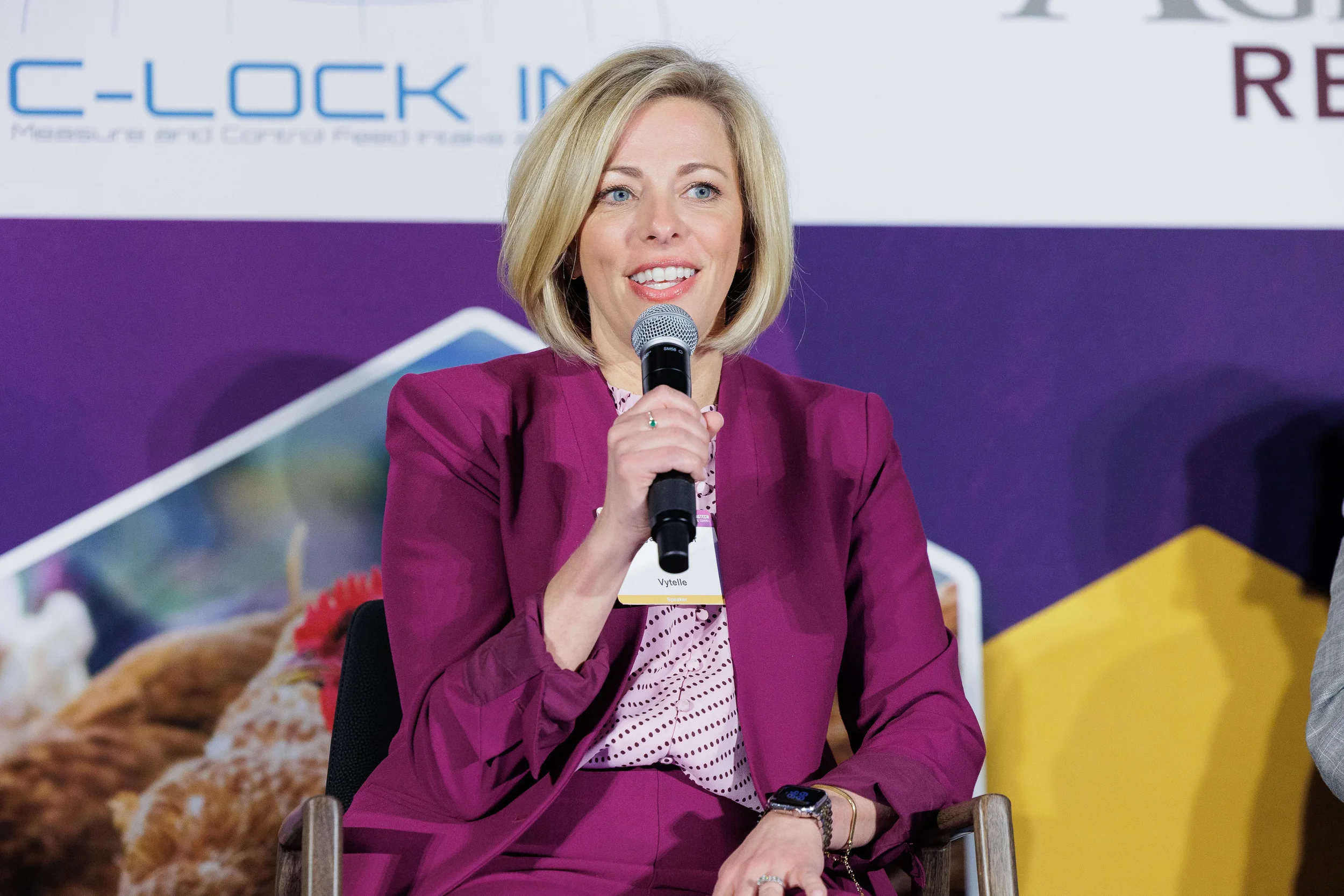 Panelist smiles while speaking into microphone during seated discussion at Chicago corporate summit