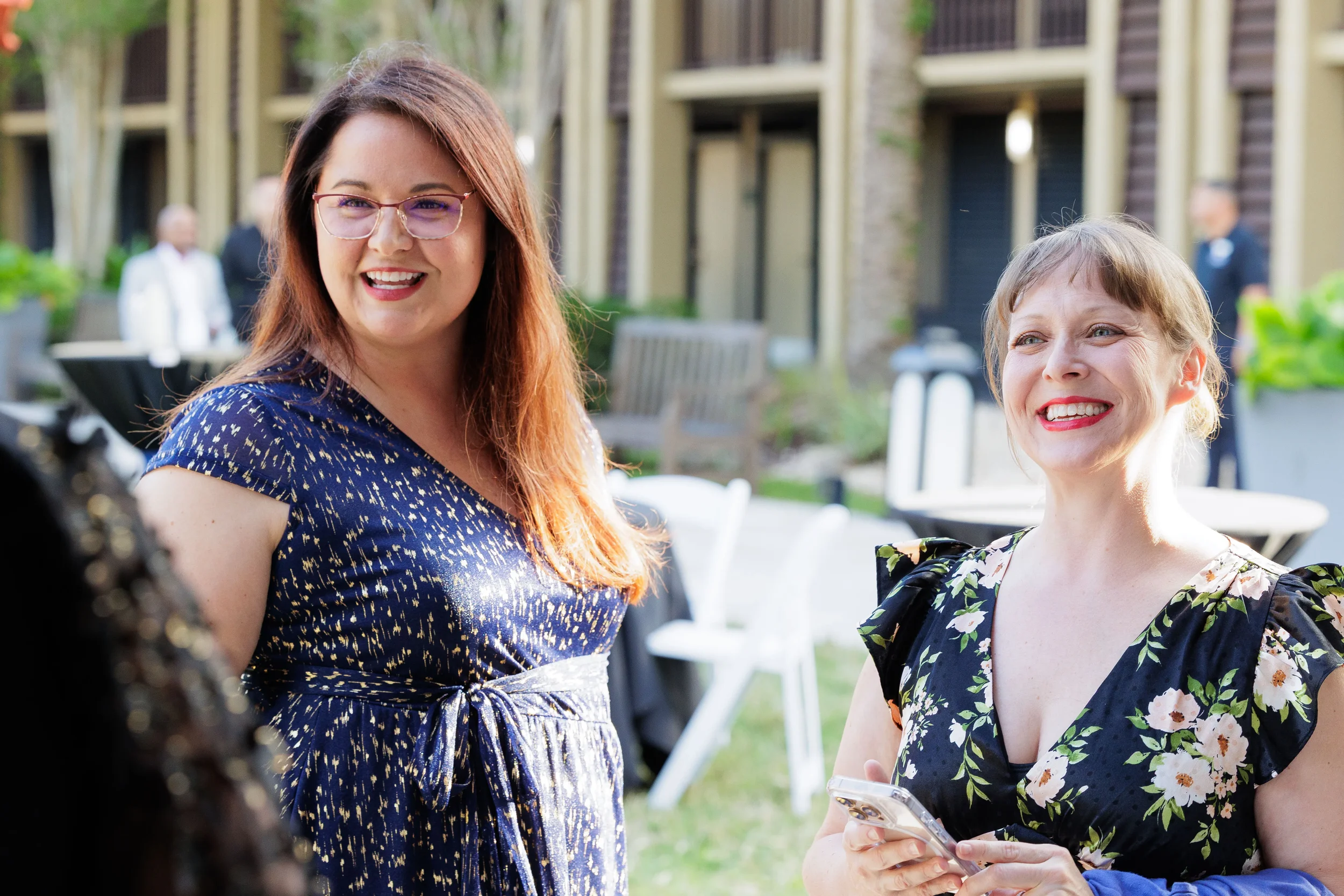 Two women smile and laugh together at outdoor courtyard networking reception at Chicago corporate event