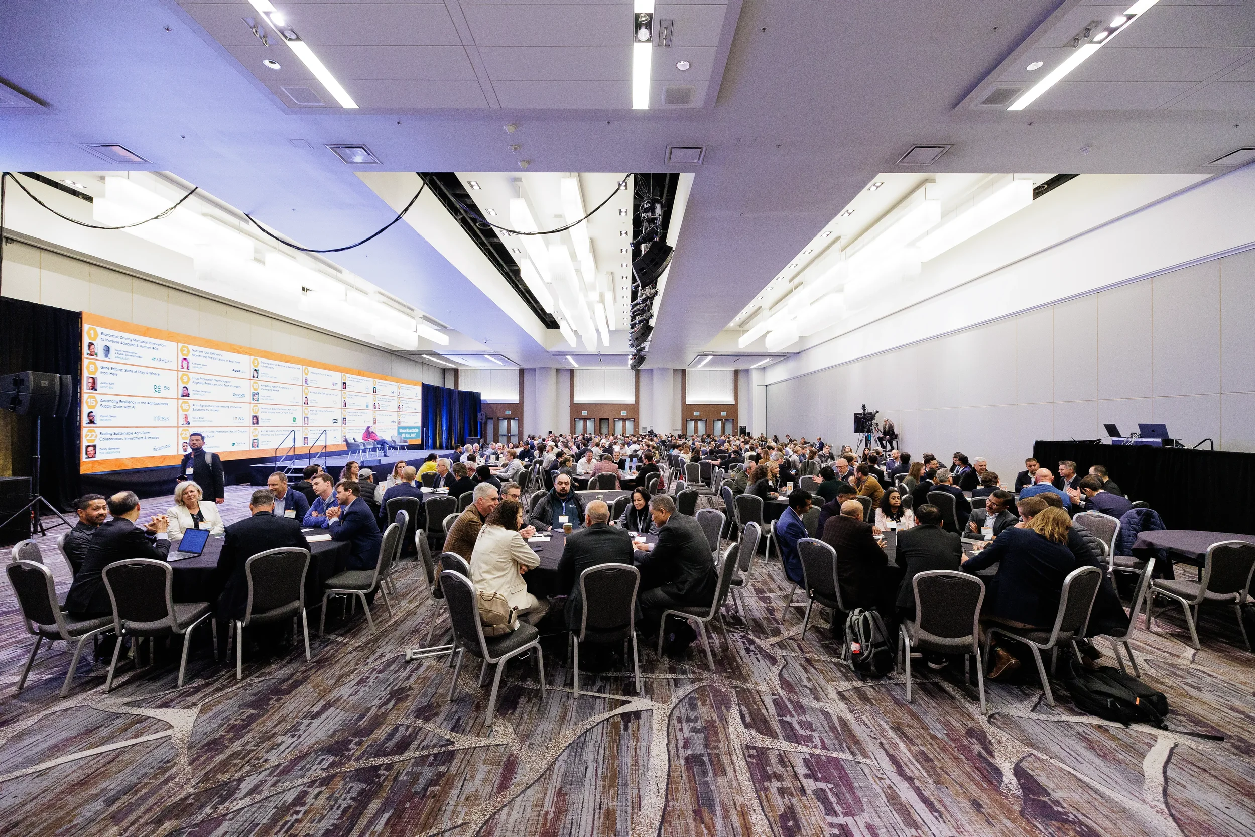 Wide view of attendees seated at roundtables during Orlando corporate conference session