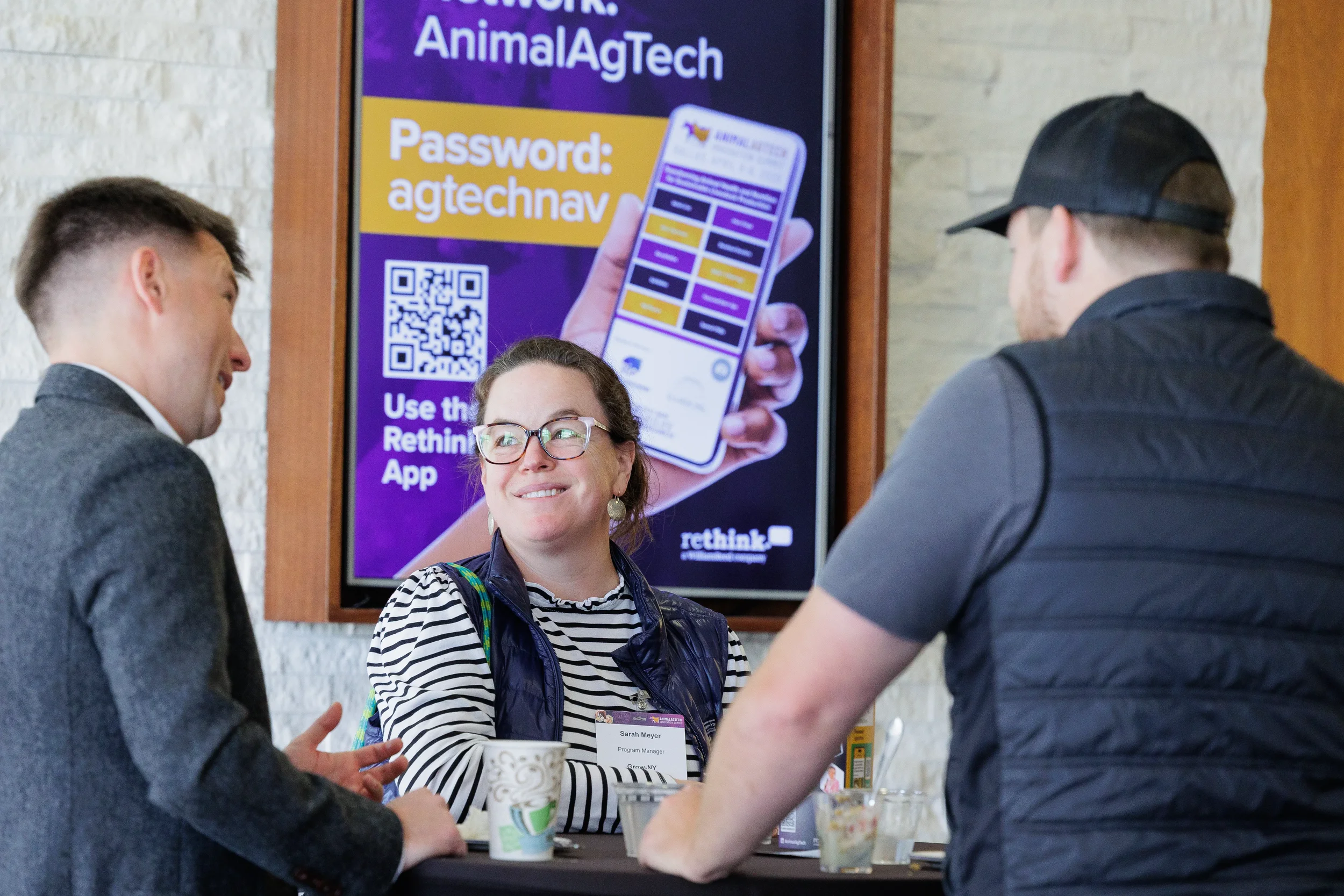 Attendee smiles while conversing at standing table at Orlando industry conference
