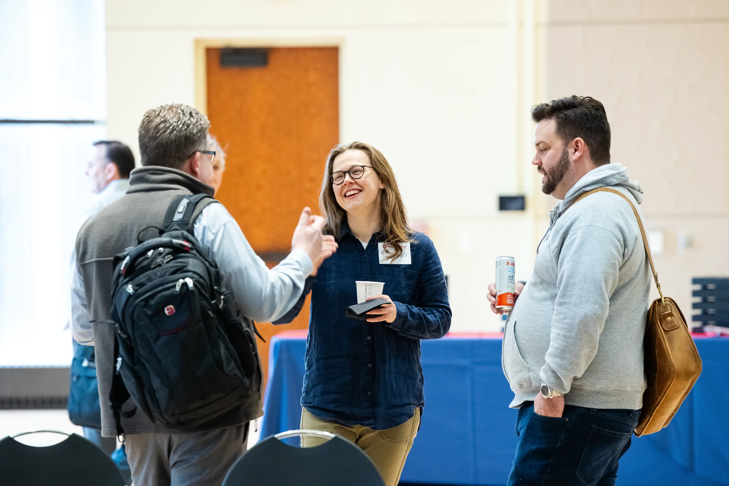 Three attendees share a laugh during networking conversation at Chicago corporate conference