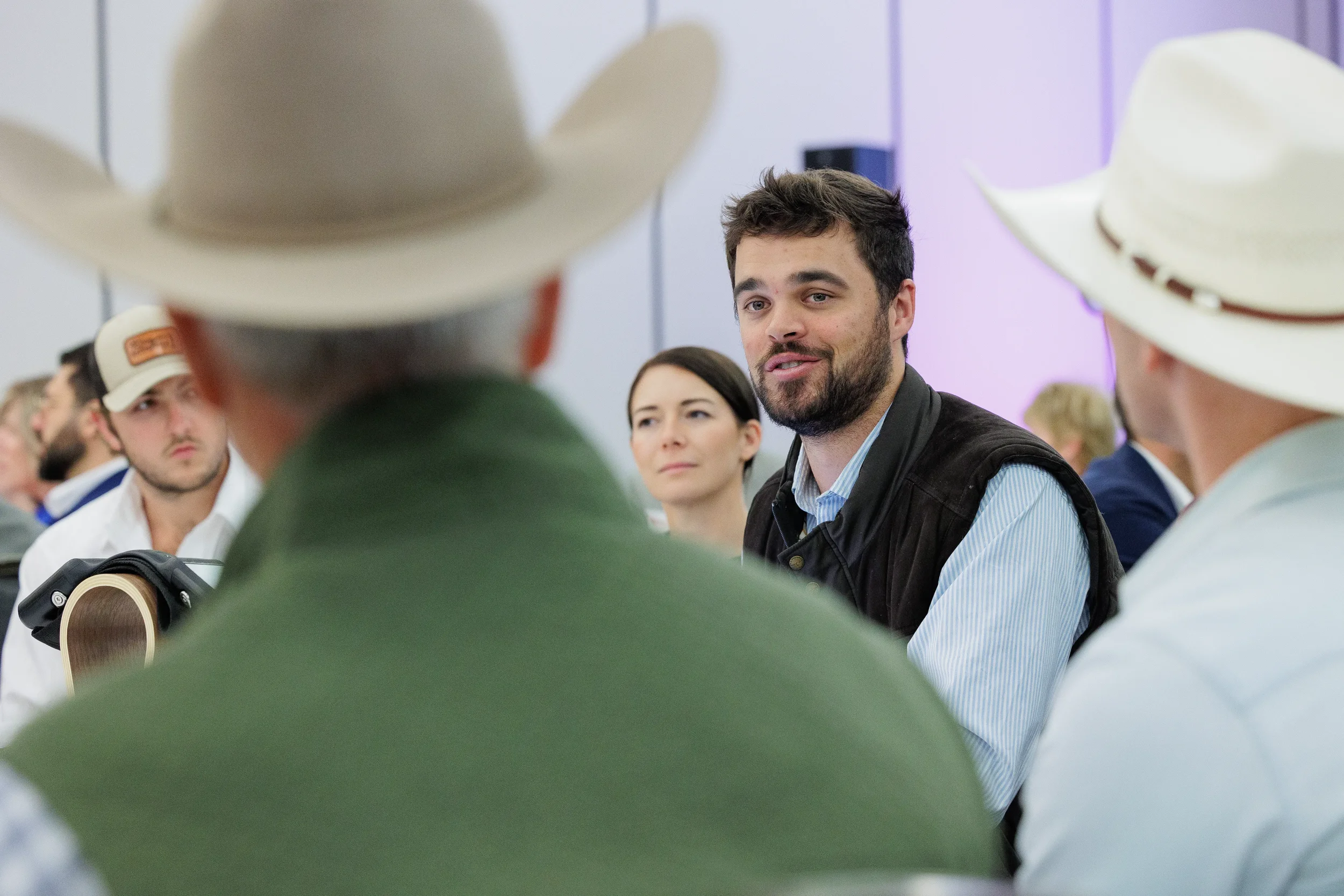 Attendee speaks with group wearing cowboy hats during Orlando industry conference