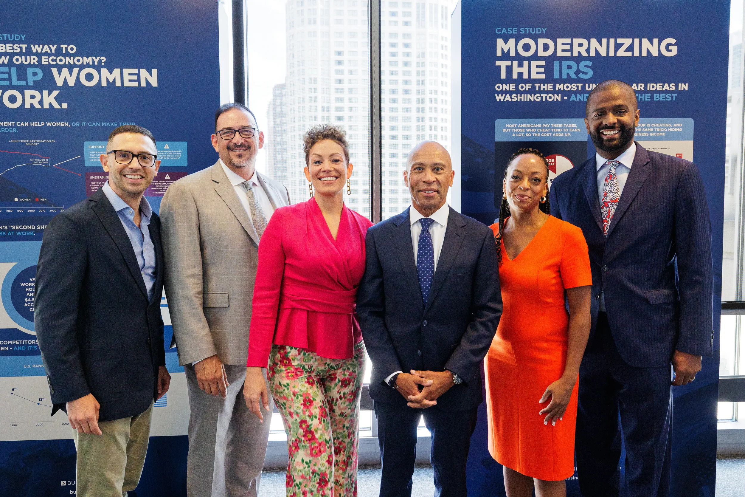 Conference speakers pose for group photo in front of branded display at Chicago corporate event