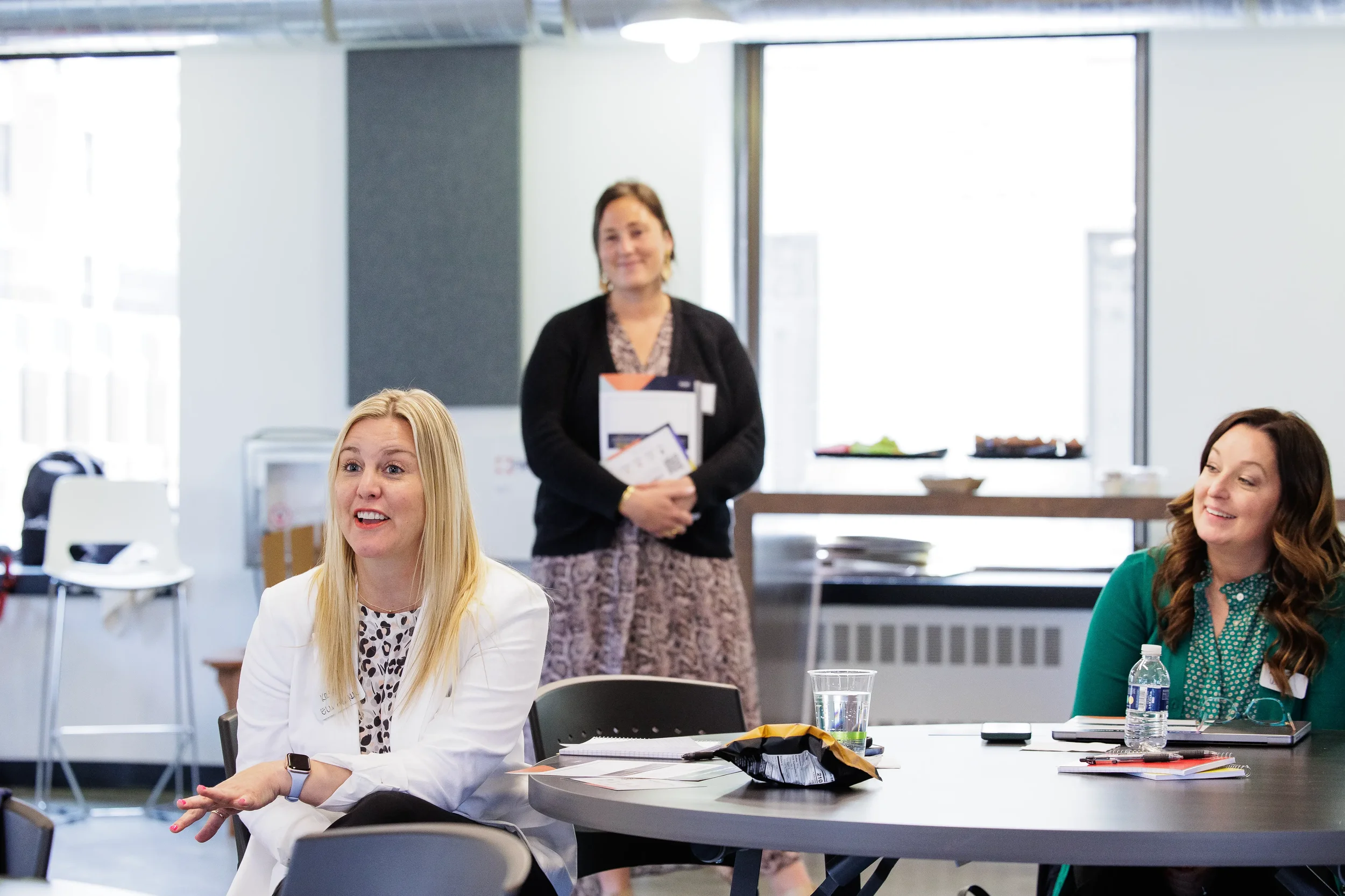 Female attendee speaks at a round table while two colleagues listen at Orlando industry conference