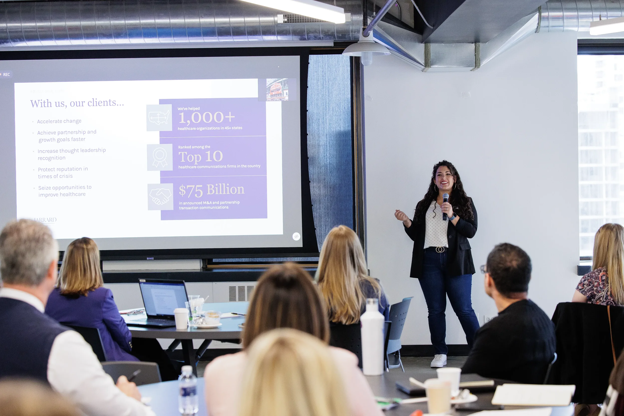 Female speaker presents beside a large statistics slide to a seated audience at Orlando corporate conference