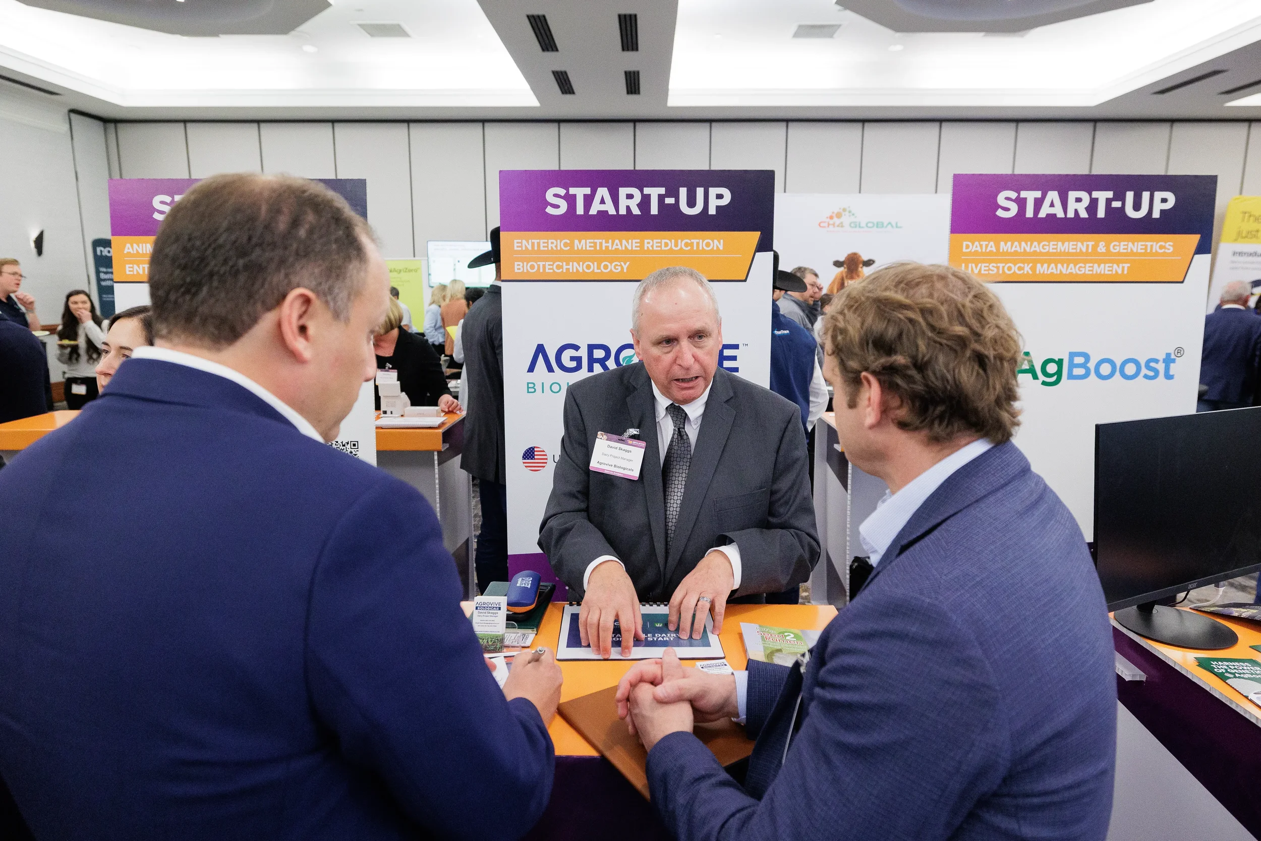 Attendee speaks with visitors at startup booth during Chicago industry trade show