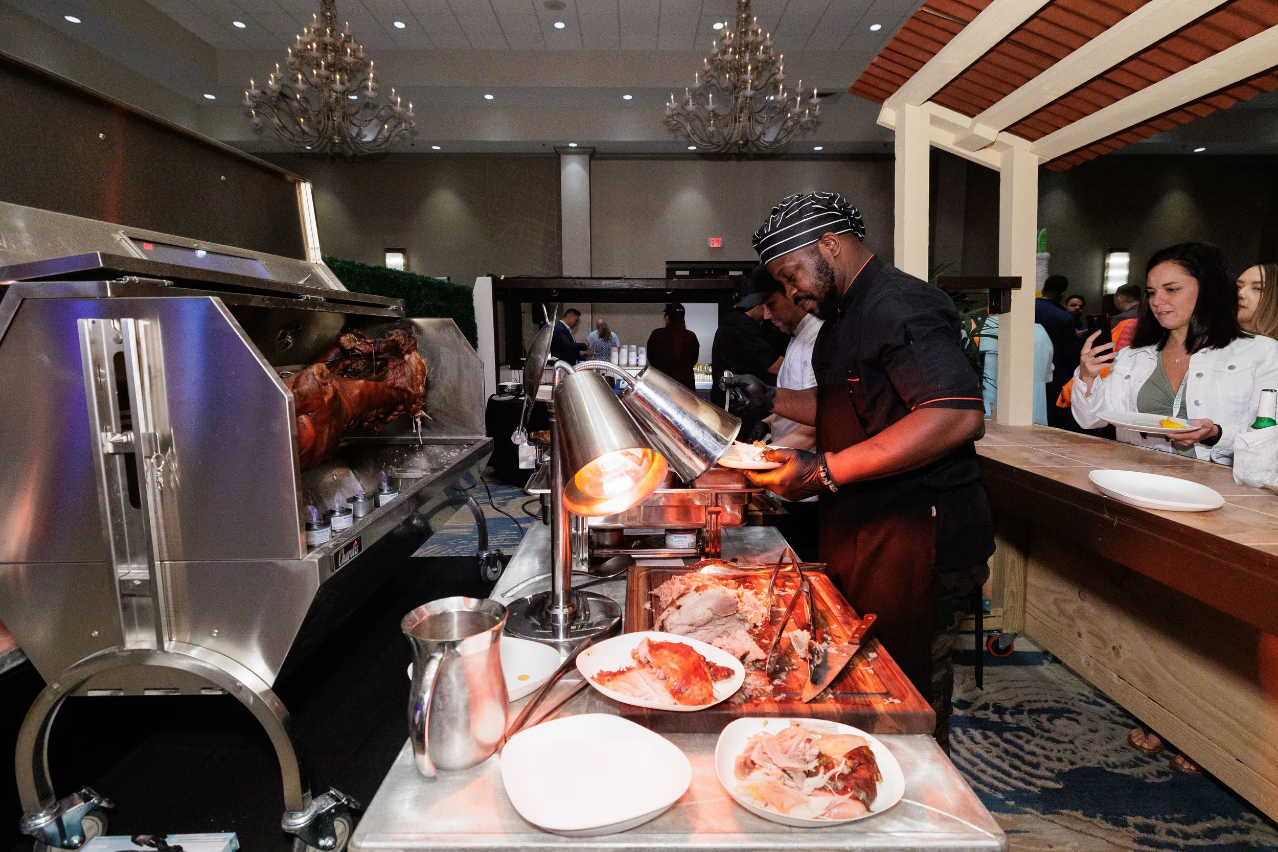 Chef in hat carves roasted meat at carving station during Orlando corporate conference expo reception