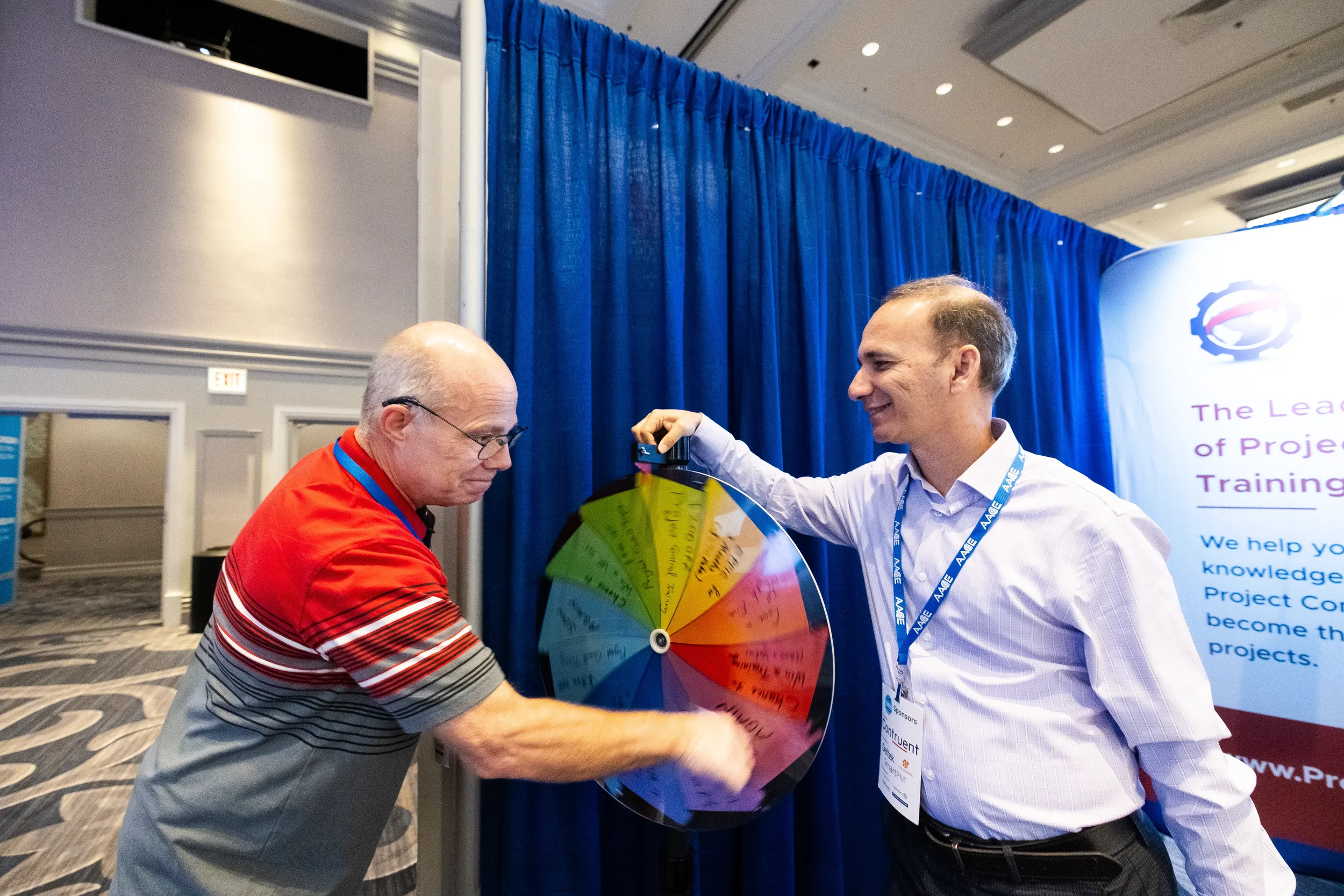 Conference attendee spins prize wheel at exhibitor booth during Orlando trade show expo