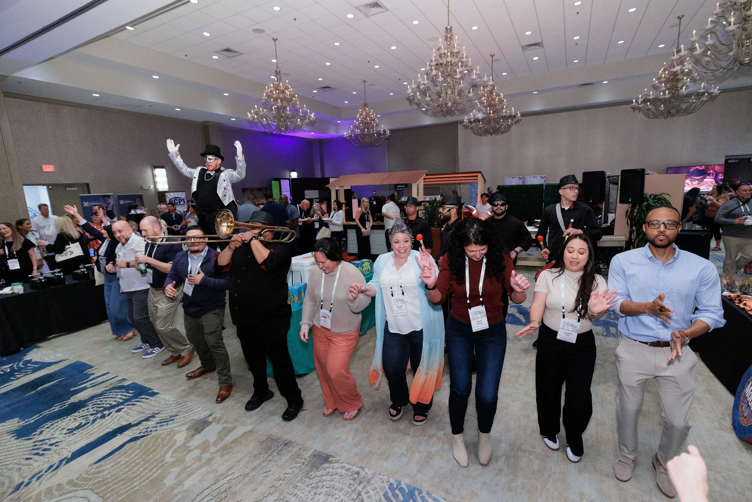 Conference attendees dance in a line alongside live band performers in chandelier ballroom at Orlando corporate event