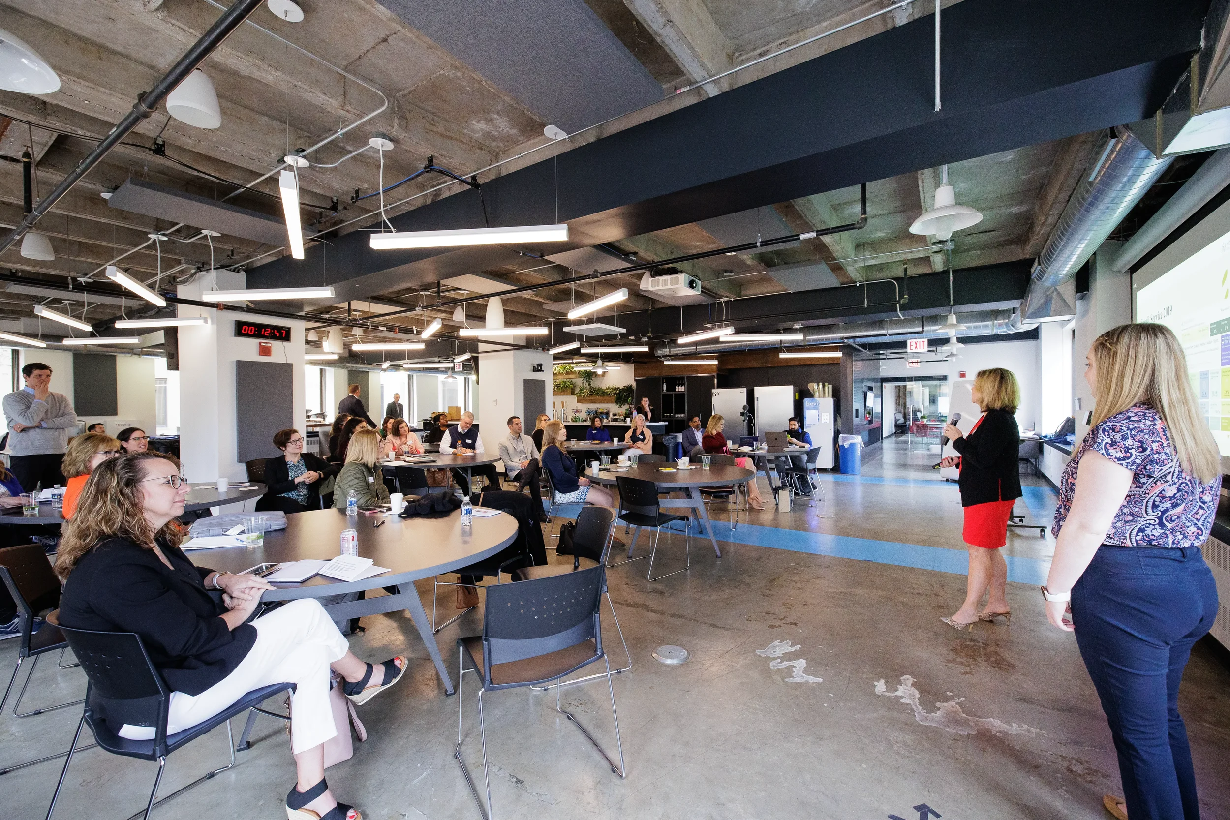 Two female presenters stand before a full room of seated attendees at Orlando industry conference