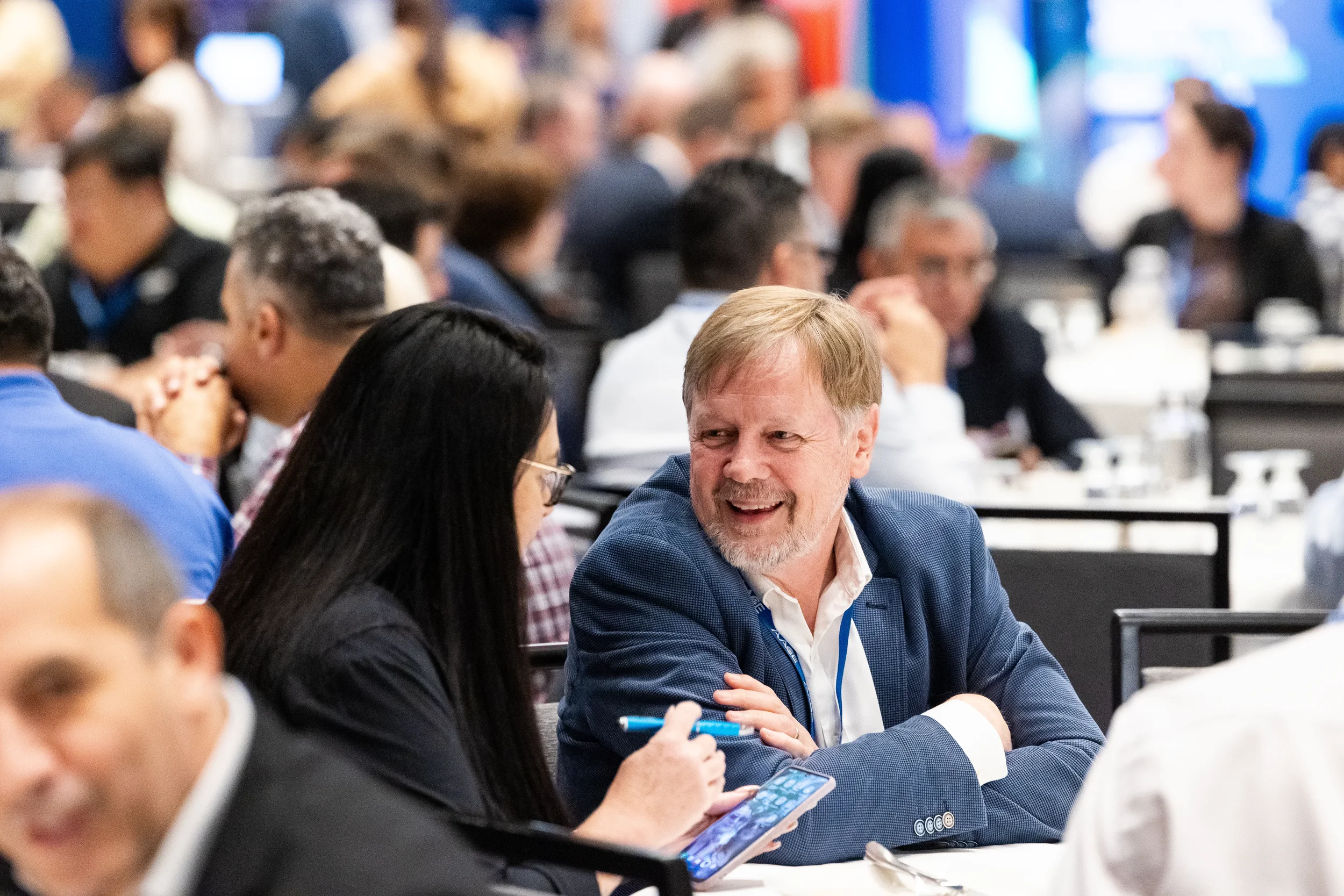 Two attendees laugh and converse at a crowded table during a networking session at a Chicago corporate event