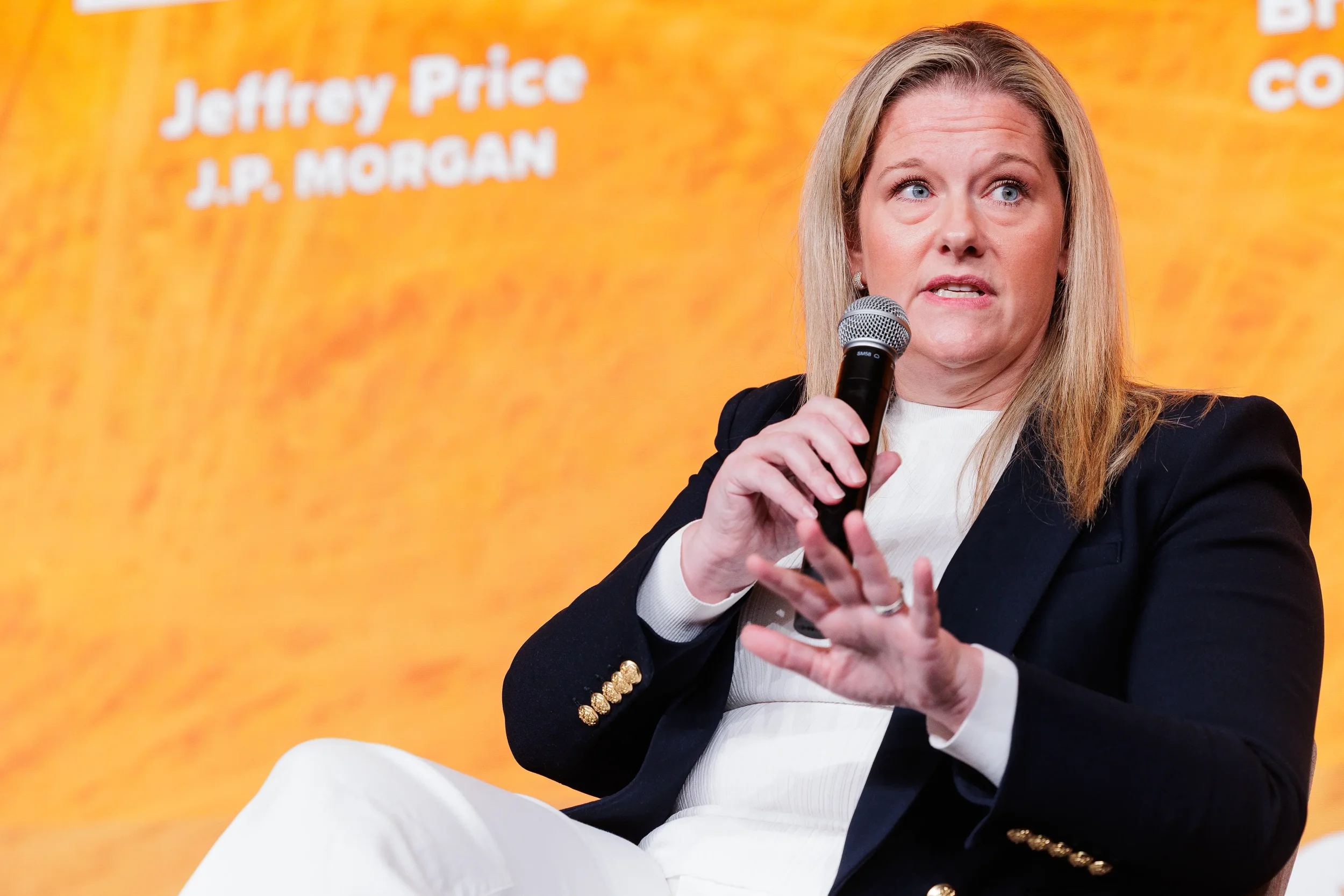 Speaker gestures while presenting with microphone during panel discussion at Orlando summit