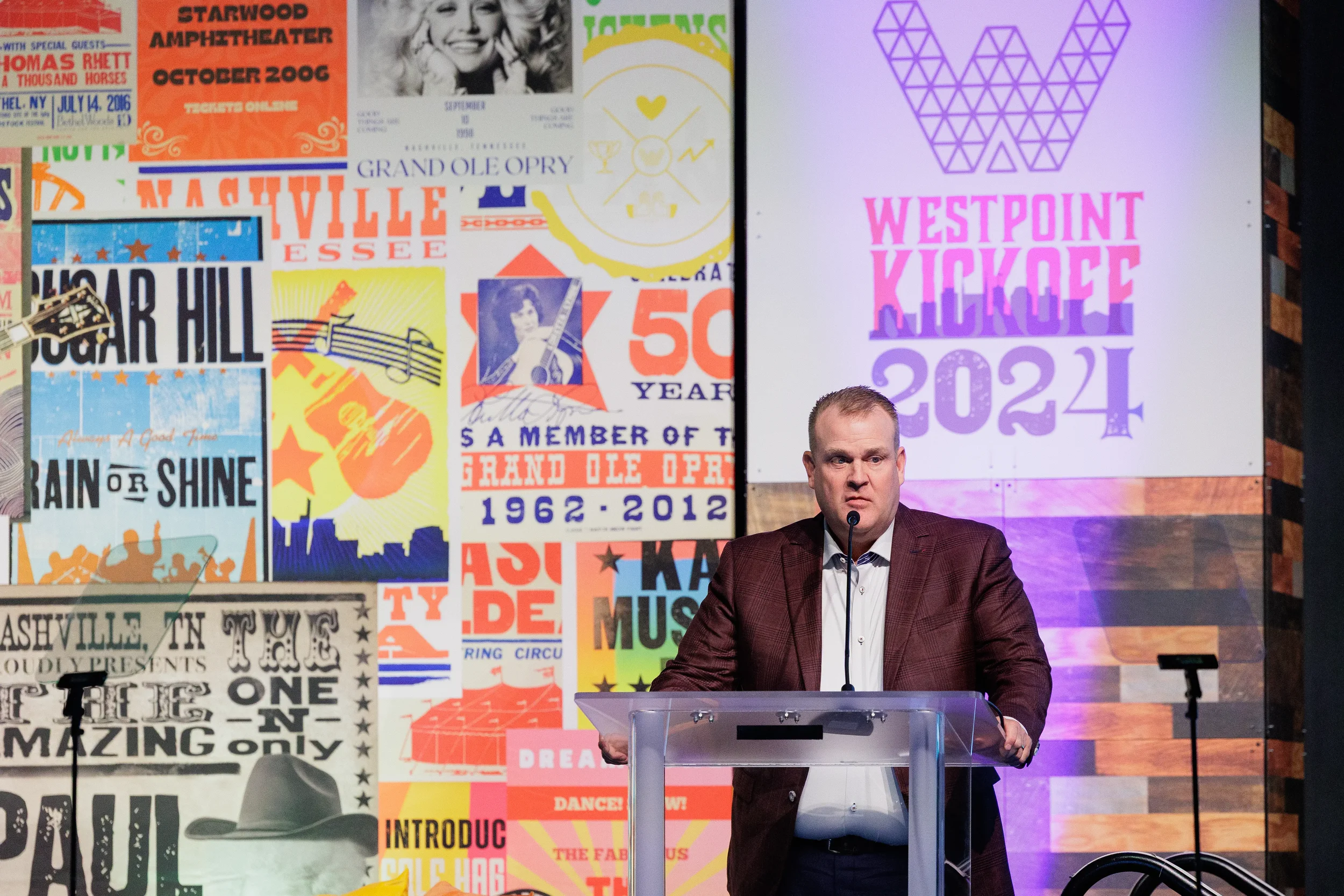 Speaker addresses audience from podium in front of colorful backdrop at Orlando corporate conference