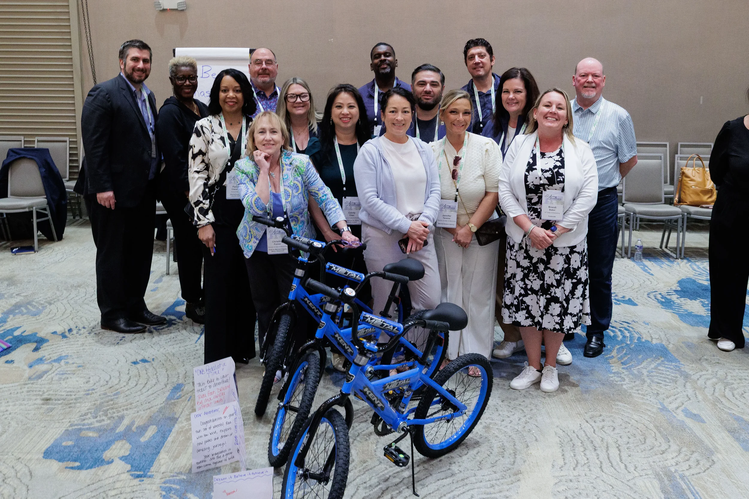 Large group of attendees poses with assembled bicycles after team activity at Chicago corporate conference
