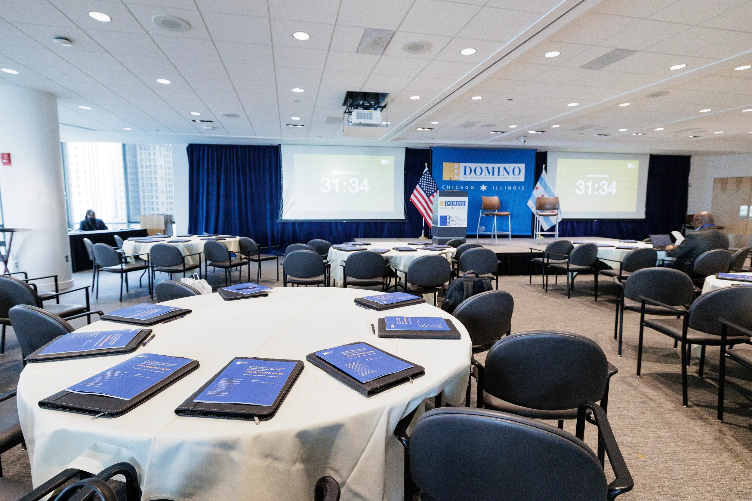 Corporate conference room set with round tables, materials, and branded stage before Orlando industry event