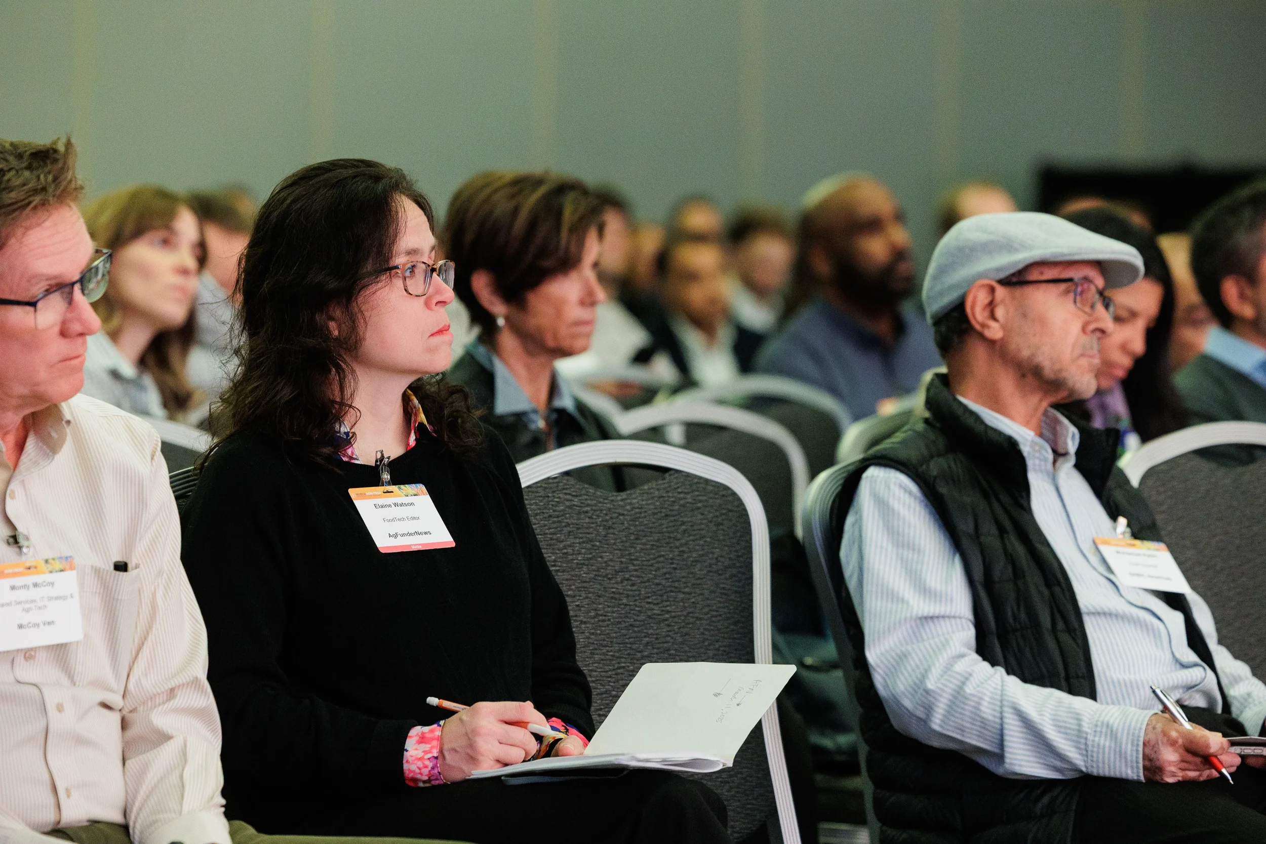 Badged attendees seated in rows listen and take notes during session at Orlando corporate conference