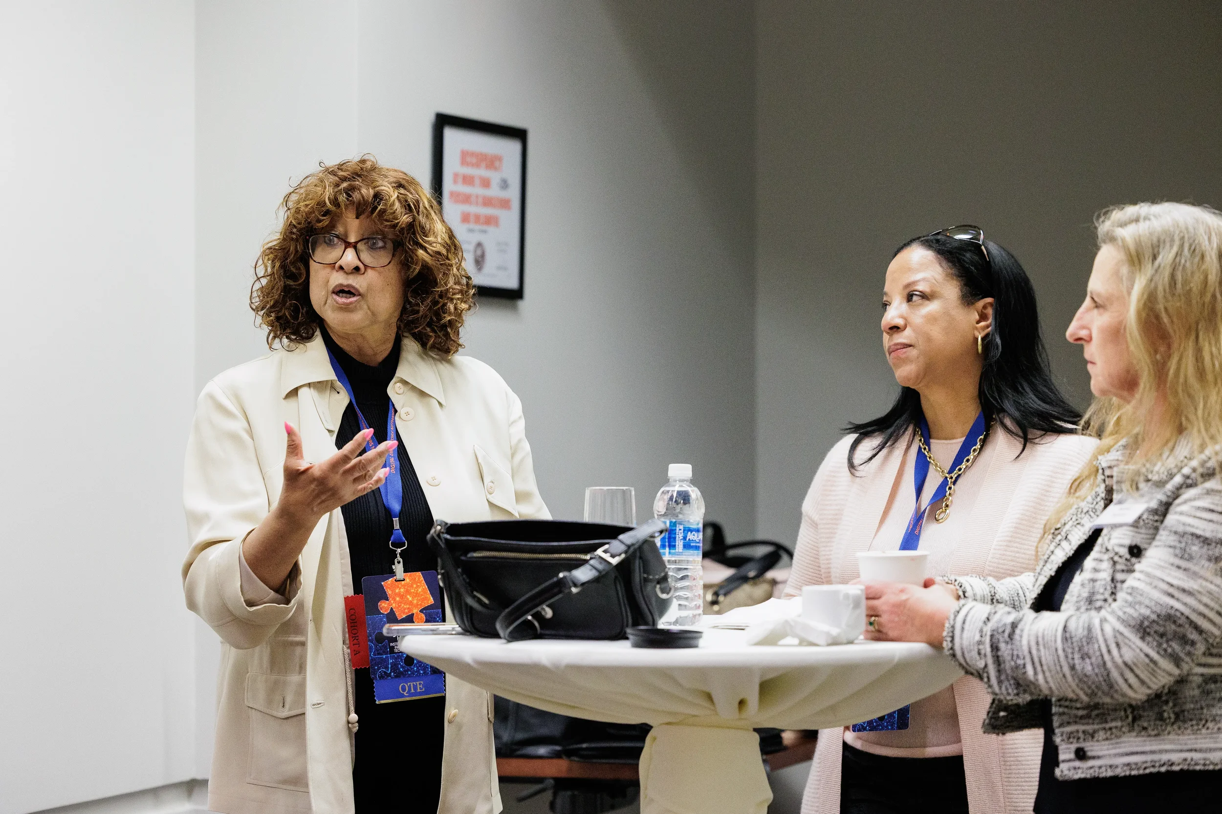 Three female attendees with lanyards converse at cocktail table during Orlando corporate event networking