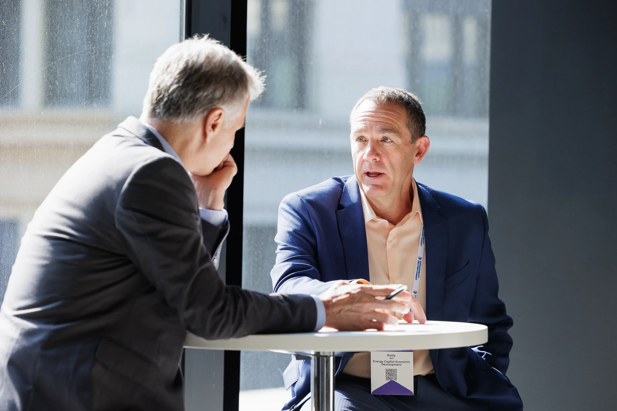 Two attendees engage in seated conversation at small table during Orlando corporate conference