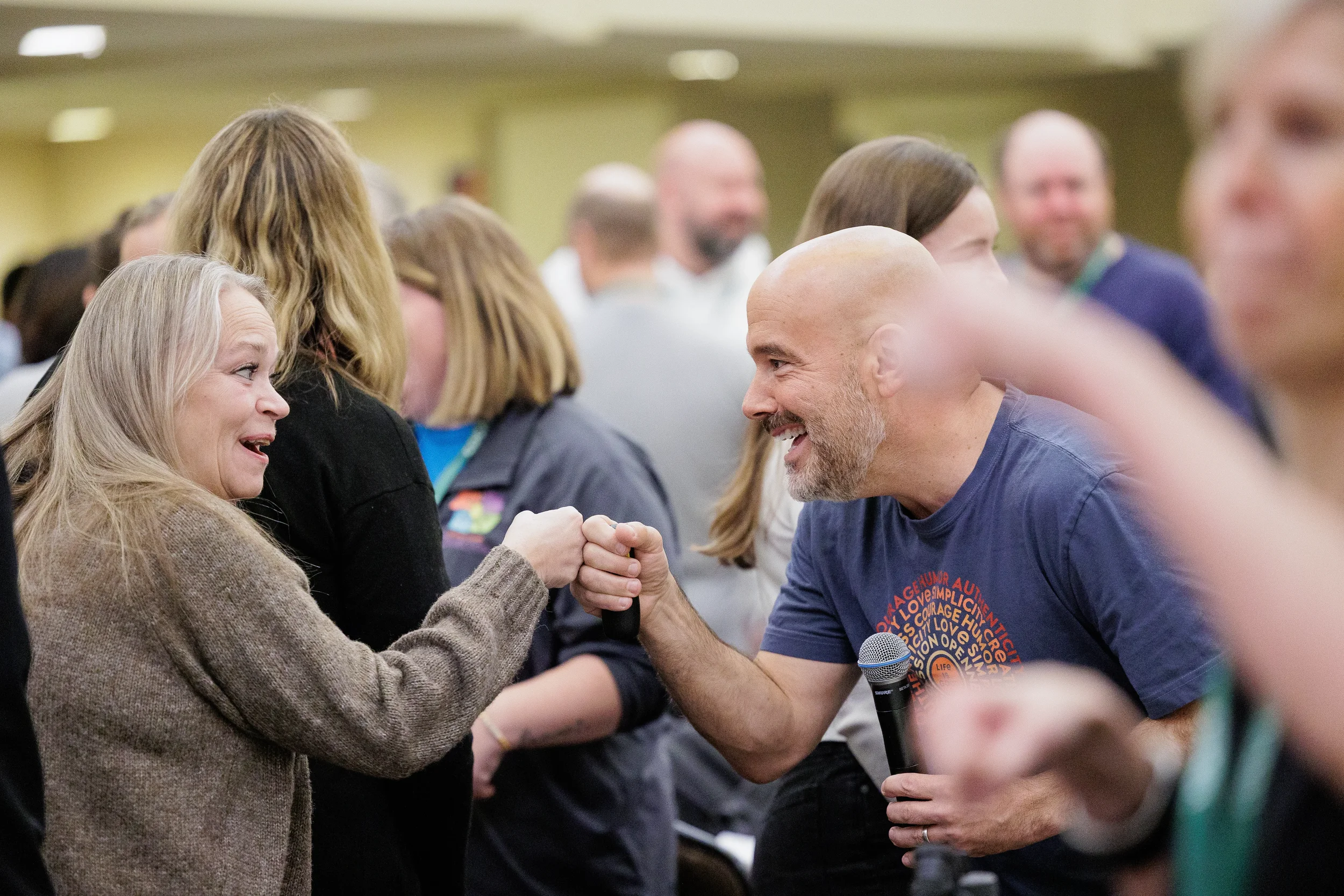 Speaker with microphone fist bumps smiling attendee during interactive session at Orlando nonprofit conference